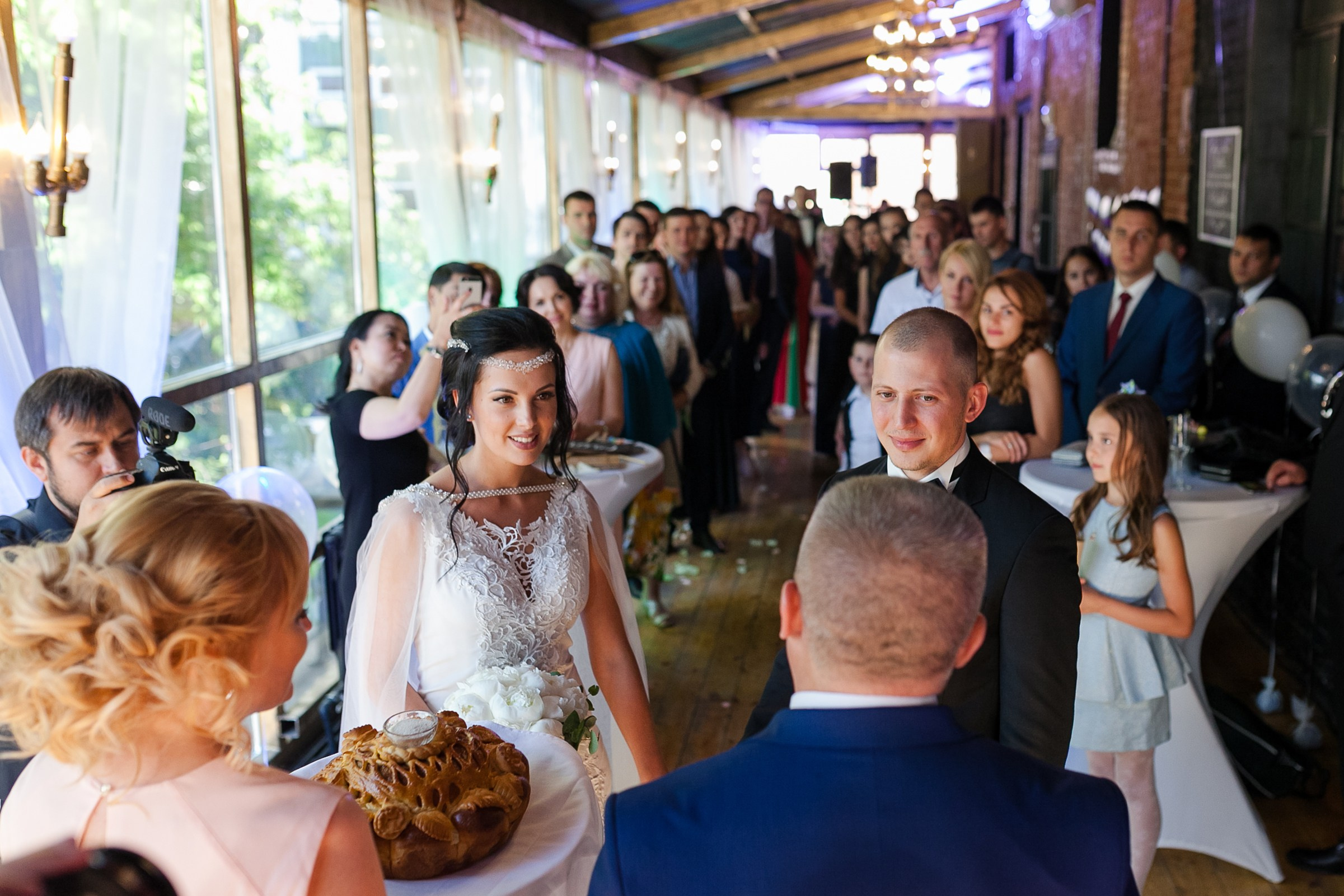 Невеста с женихом смотрят на родителей и каравай