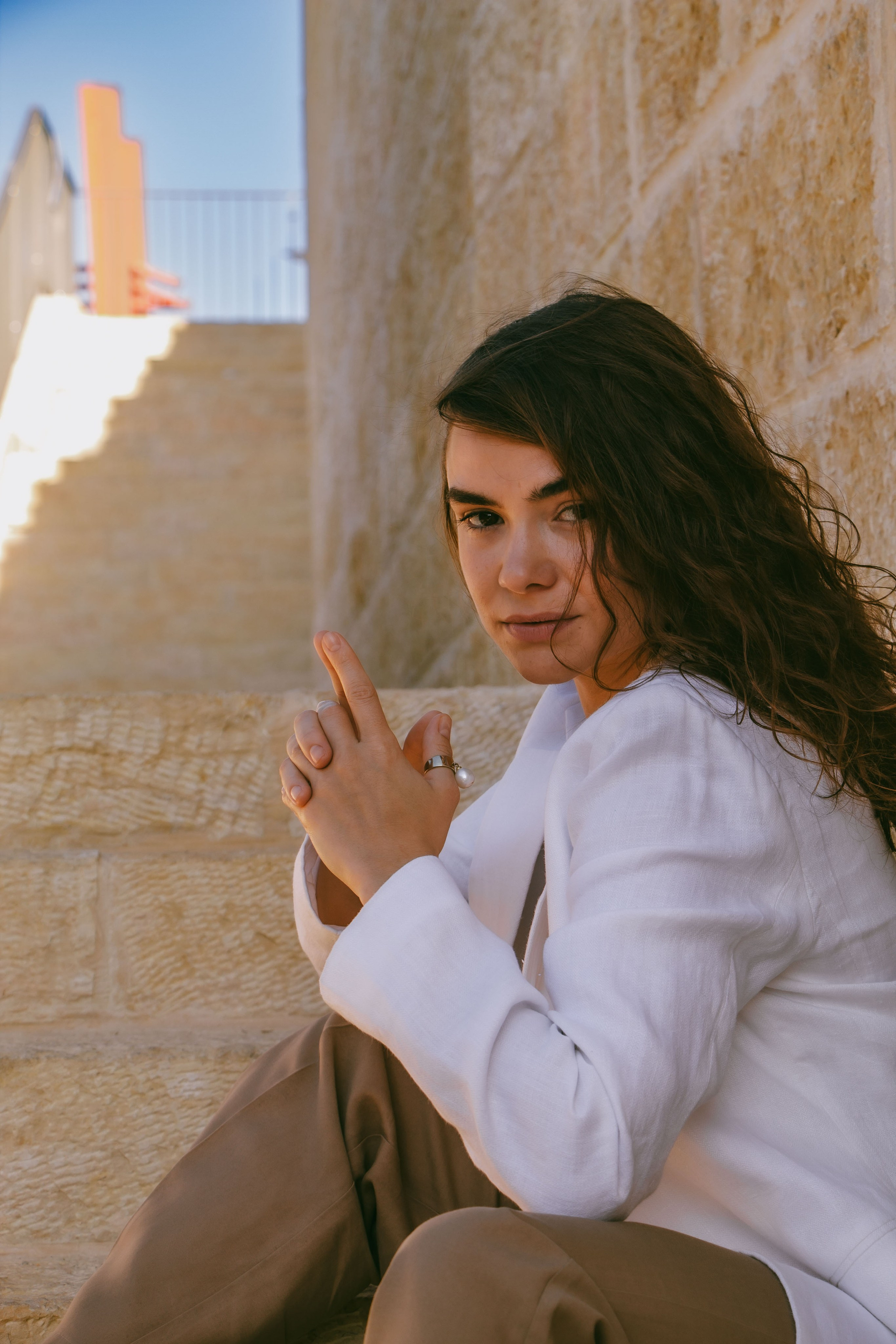 девушка сидит на ступеньках в белом пиджаке