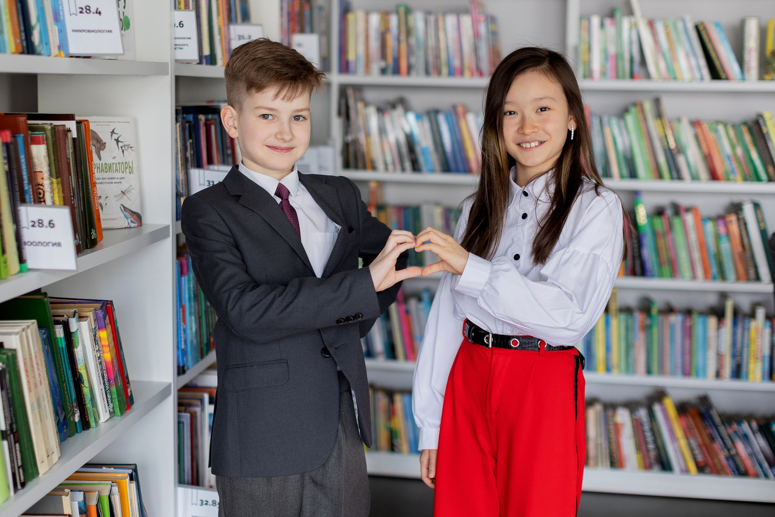 Мальчик и девочка делают сердечко из ладошек