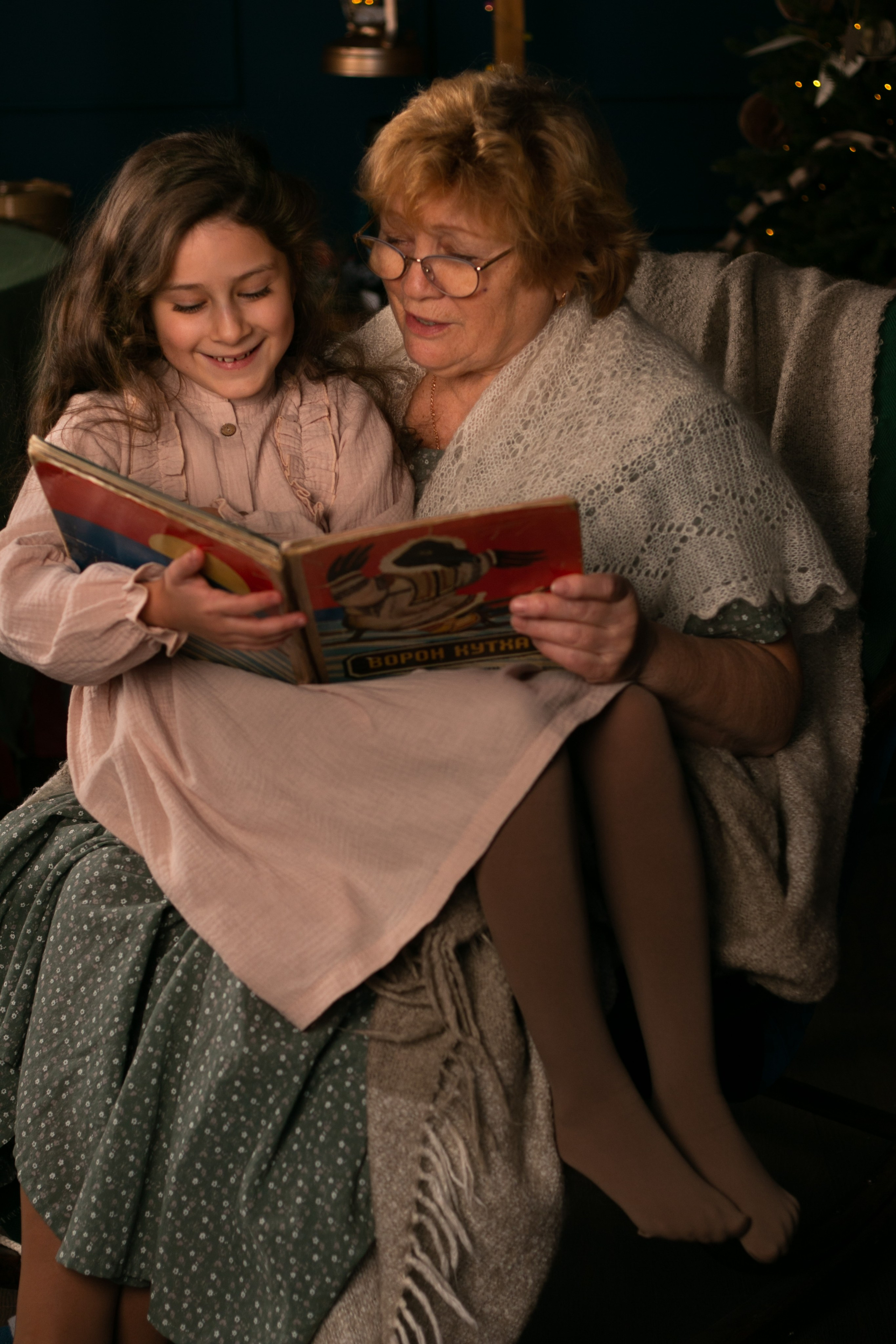 Моменты любви: бабушка читает книжку внучке, спокойный вечер, мягкие подушки, дедушкины очки