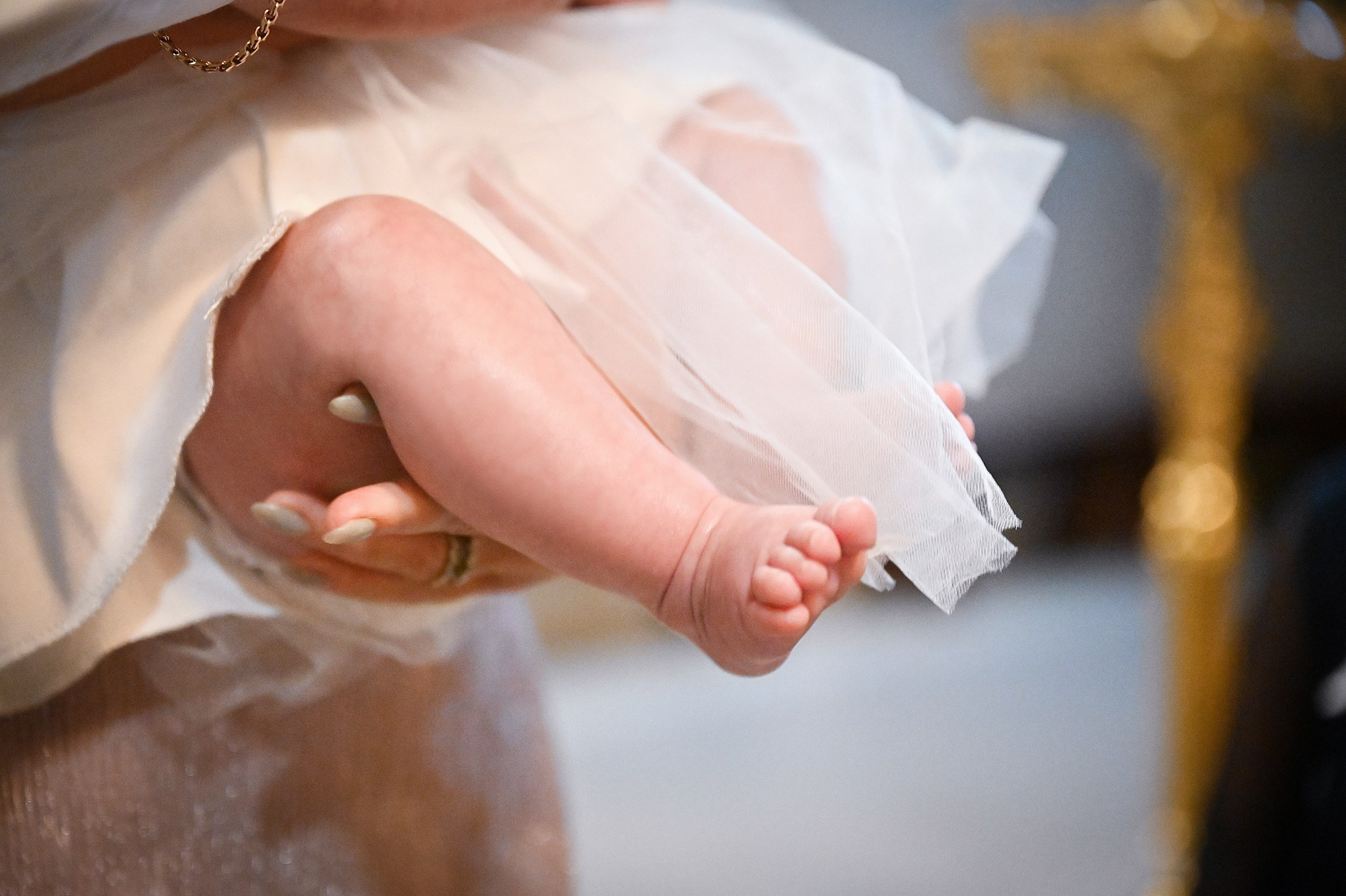 Ребенок с босой ножкой в белой крестильной рубашке