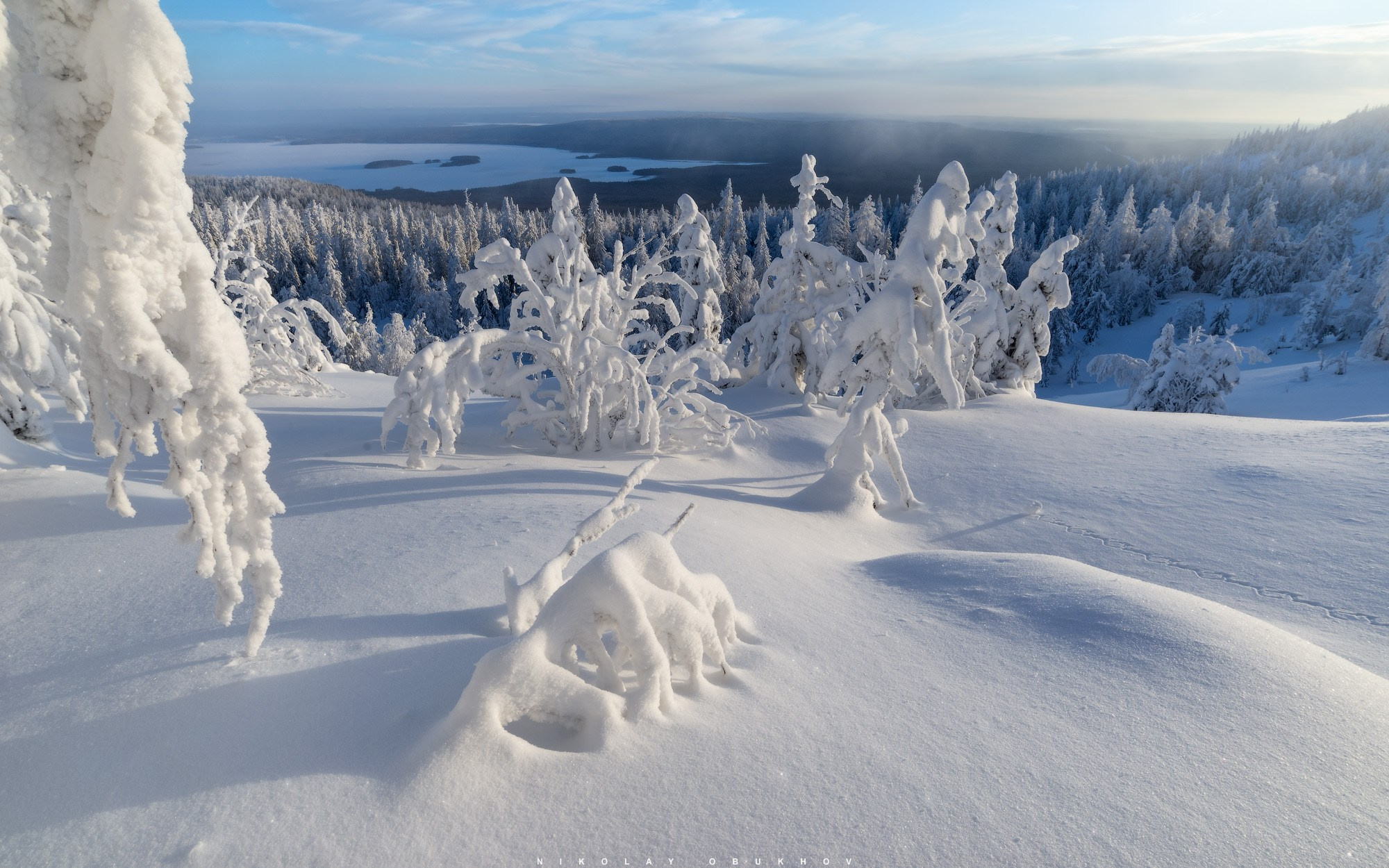 ГЛК Гора Белая и зимний лес под снегом на фоне яркого солнца.