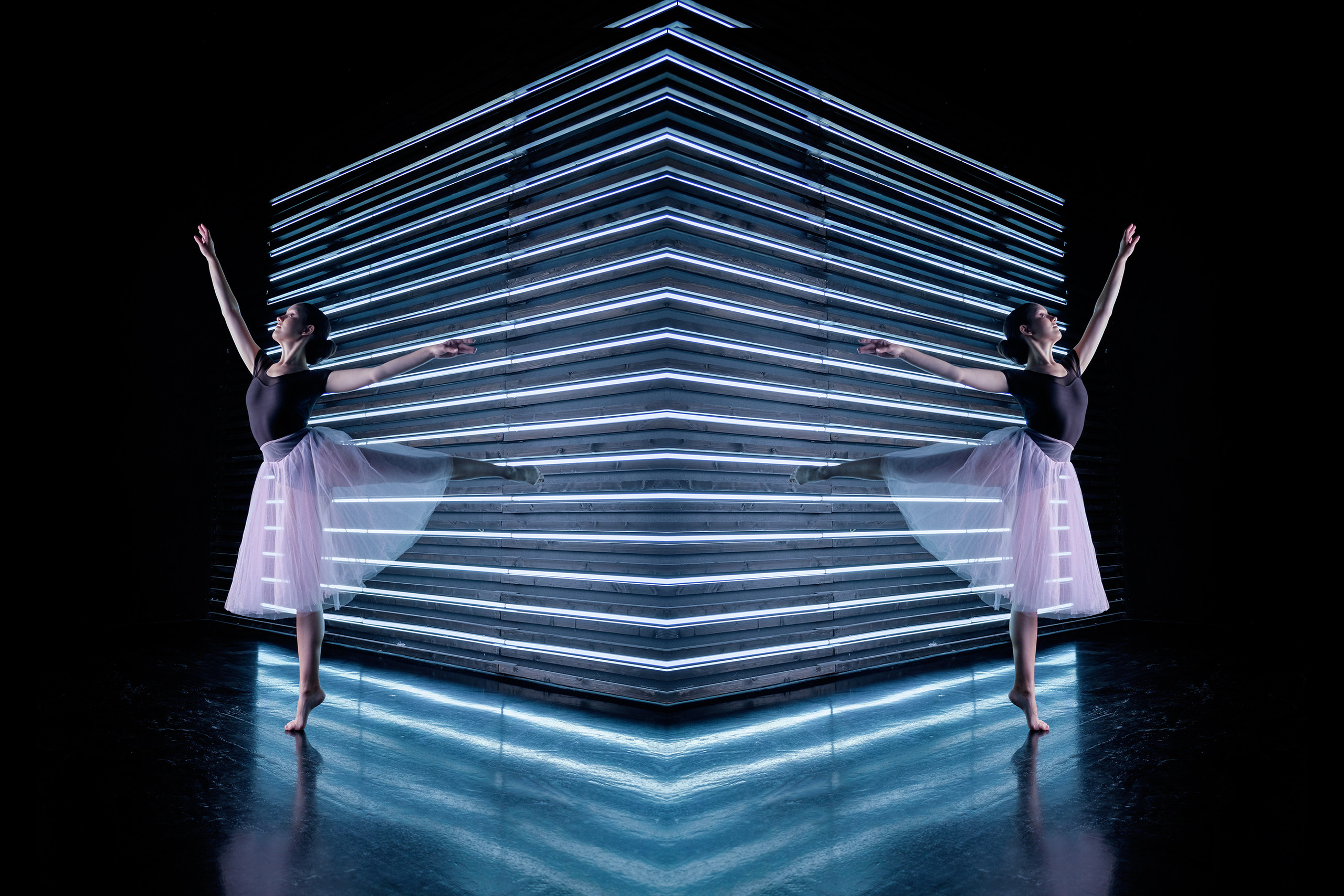 Балерина в черном трико и розовой юбке стоит в красивой позе у стены из неоновых ламп . Фотоколлаж из двух фотографий.