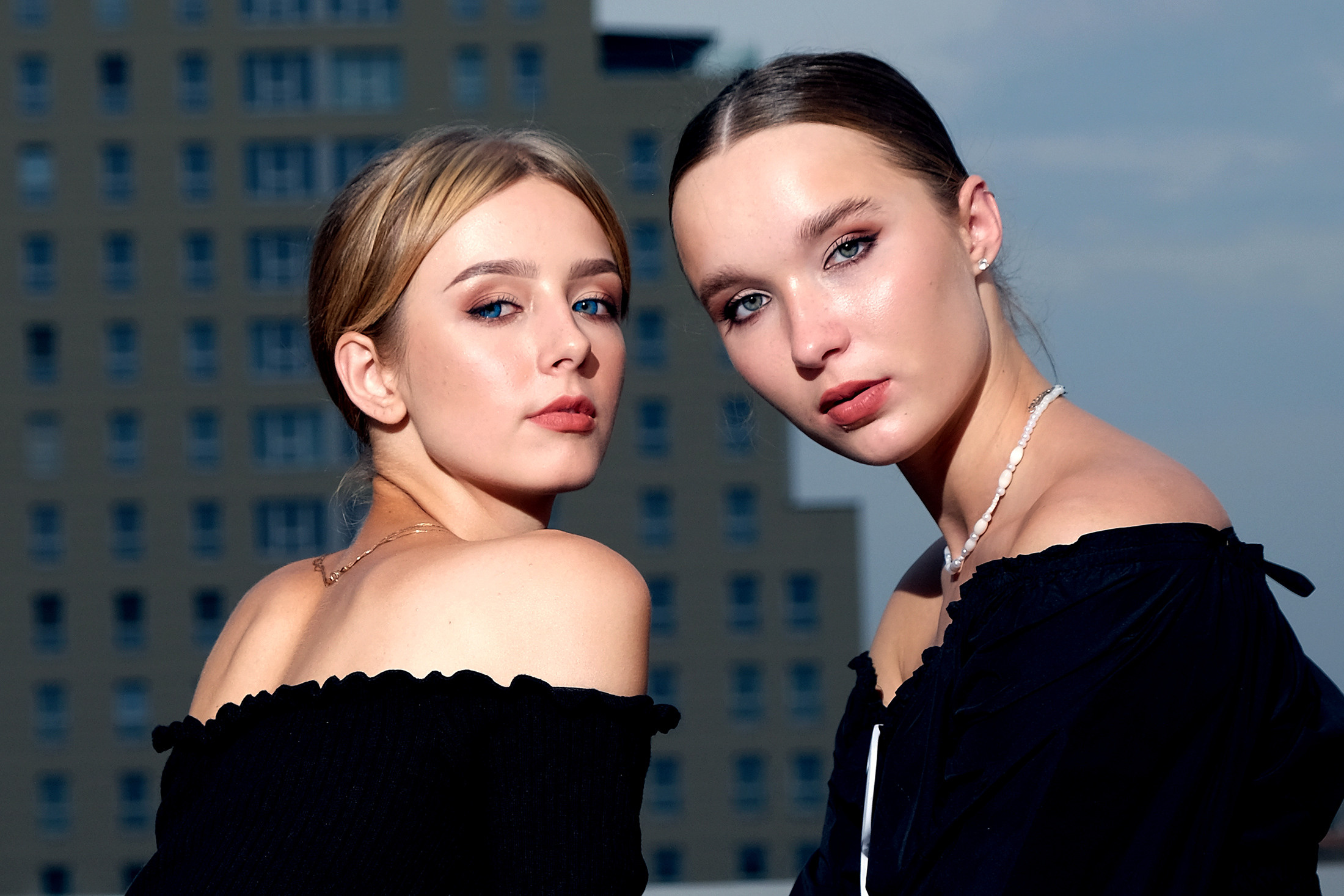 Две девушки в платьях с открытыми плечами смотрят в камеру .Вечер,закат.