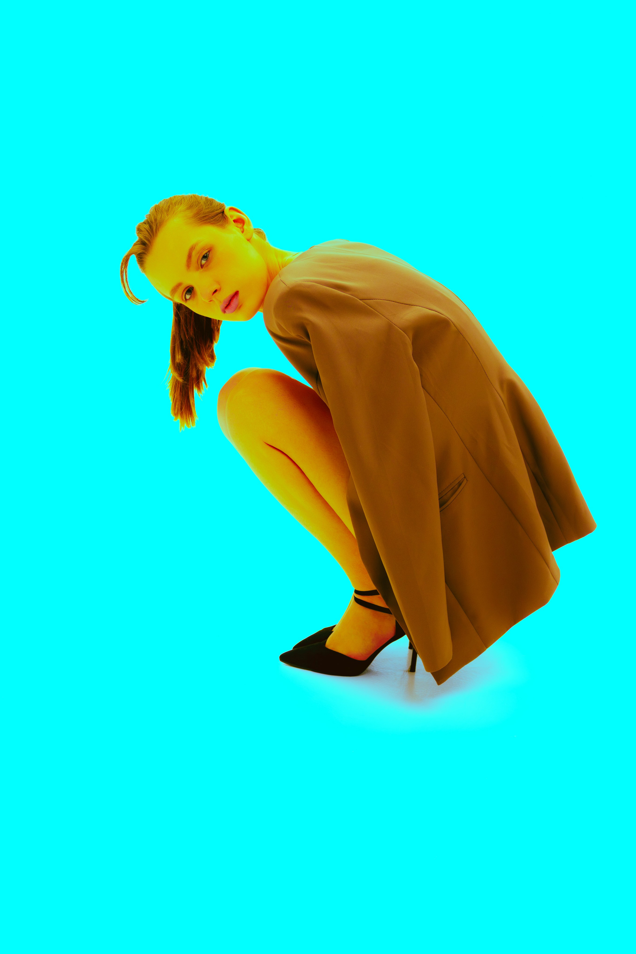 Яркая поп-арт съёмка: девушка в стильном образе шагает на фоне насыщенного голубого цвета. Акцент на обуви и силуэте подчёркивает модный характер кадра.