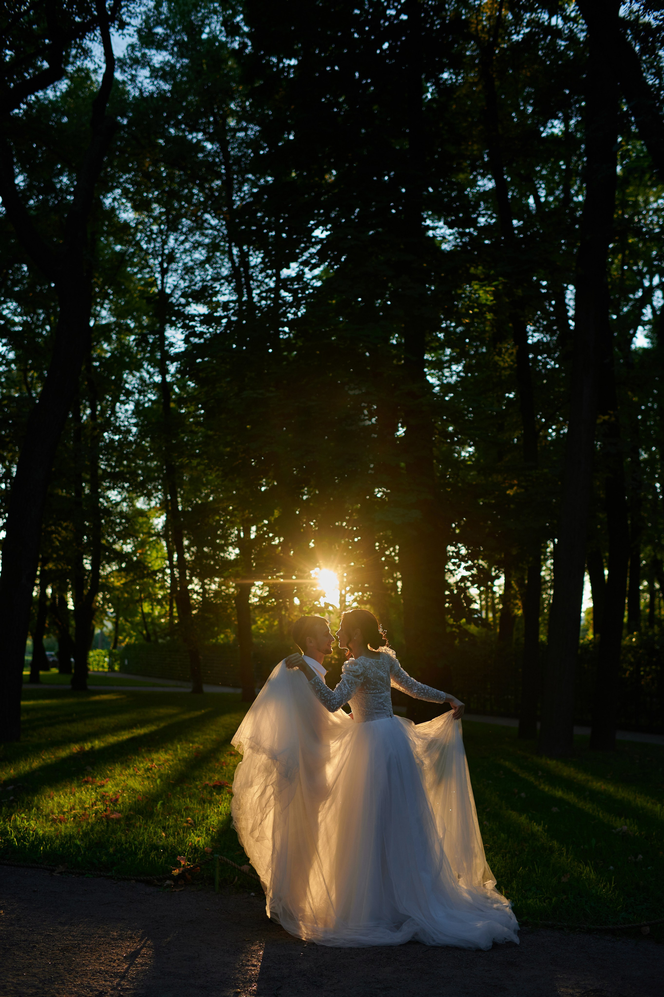 Жених и невеста в золотой съёмочный час позируют в лучах заходящего солнца