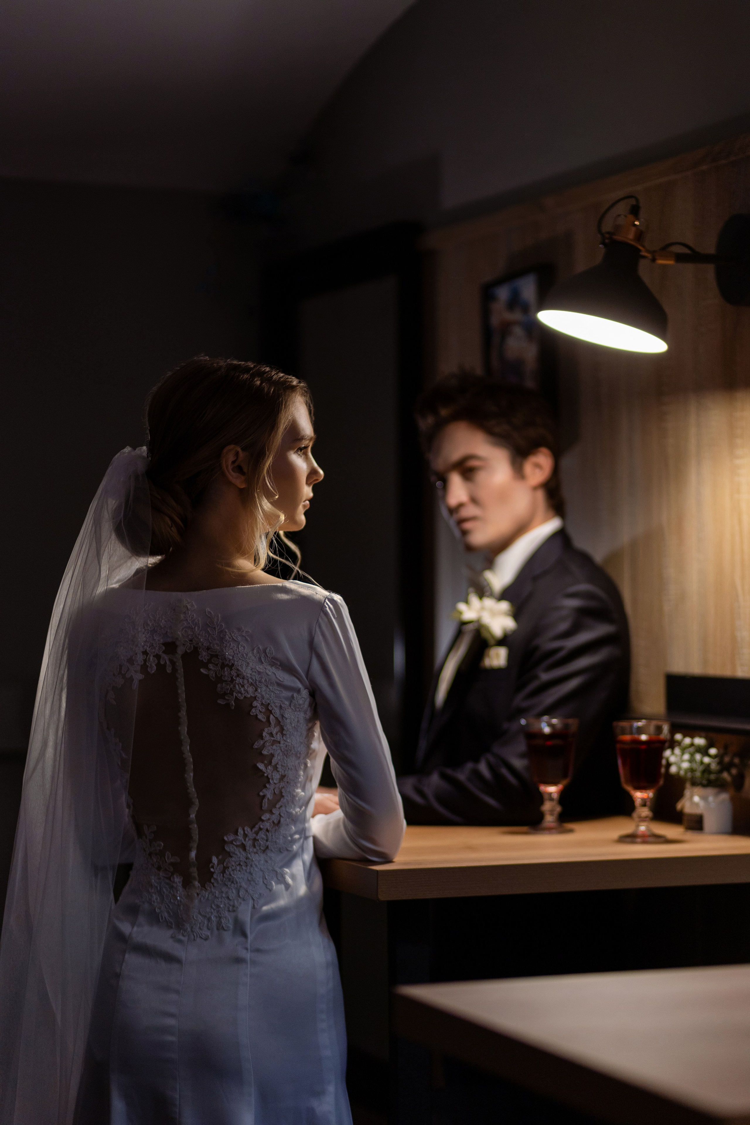 Невеста стоит у стола с женихом, по разные стороны.