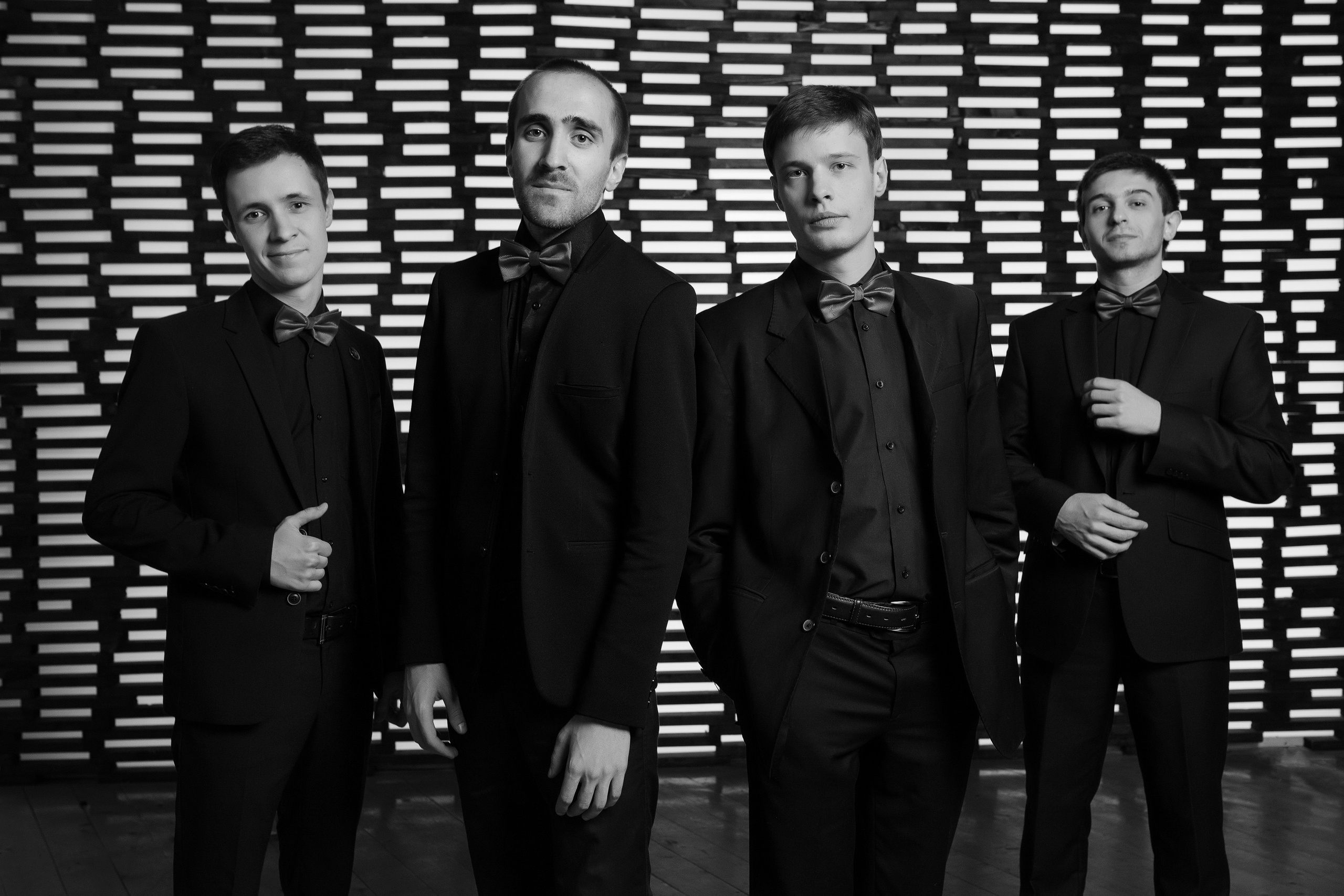 Мужской квартет музыкантов инструменталистов на необычном полосатом фоне