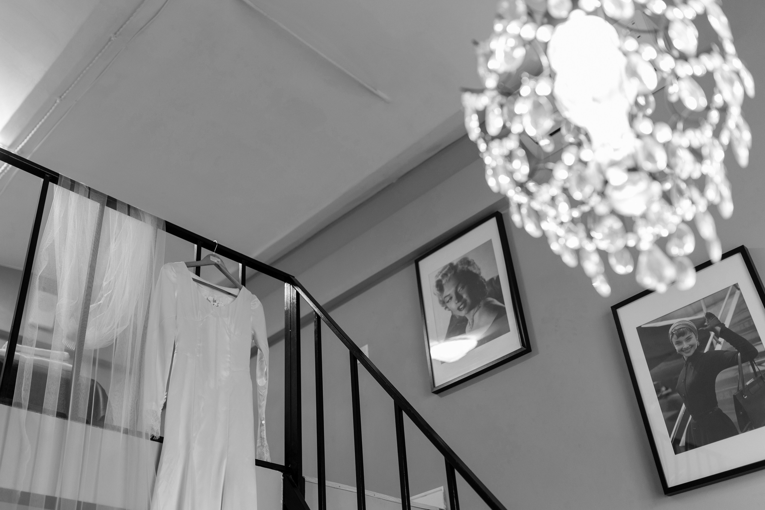 Платье невесты на тремпеле висит на перилах лестницы.