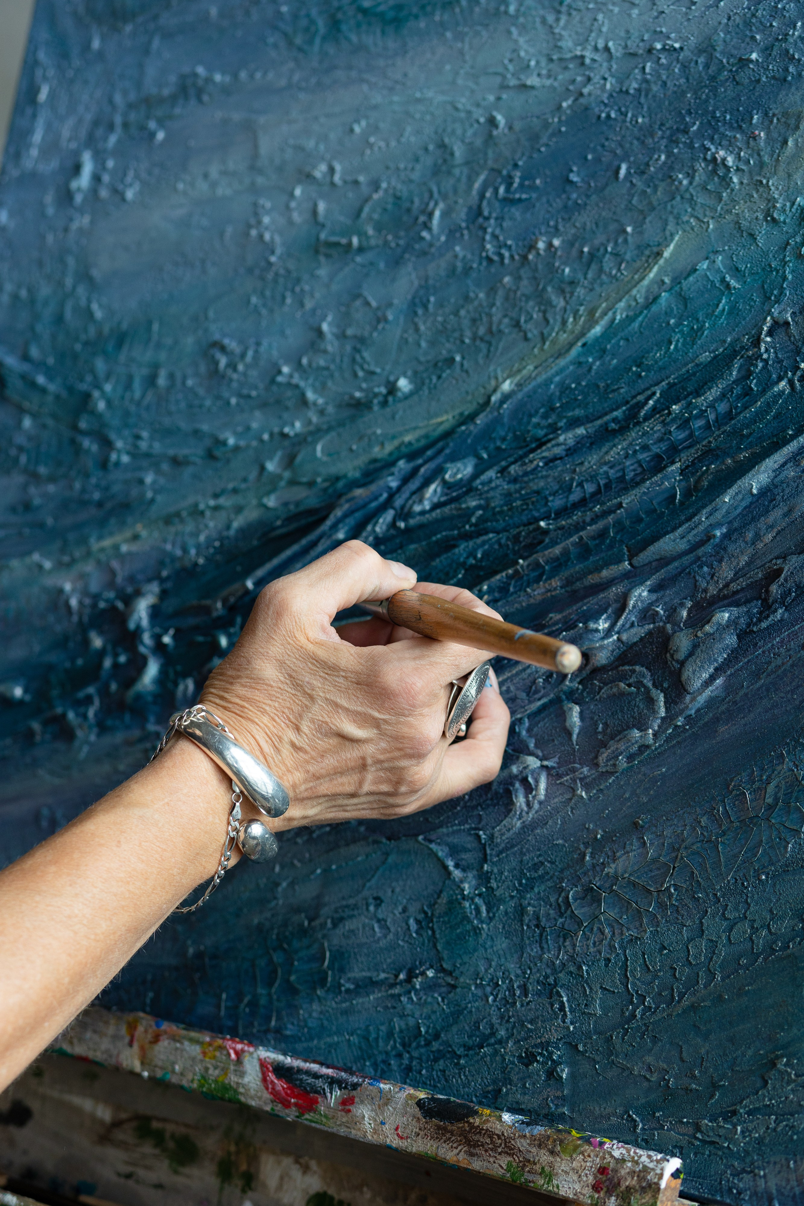 На фотографии рука художницы, проводящая мазки по холсту  