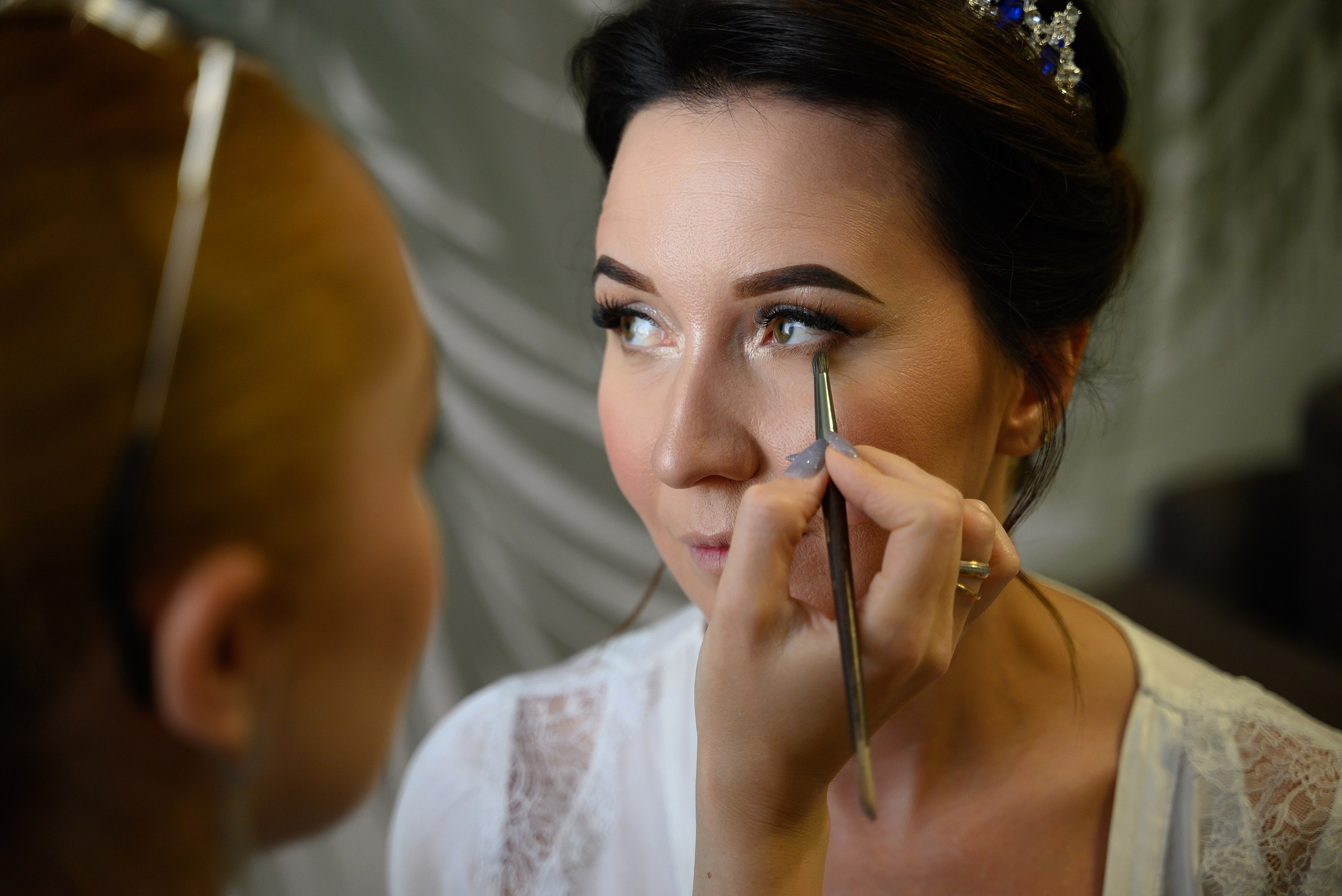 Фотография как визажист делает макияж невесте.