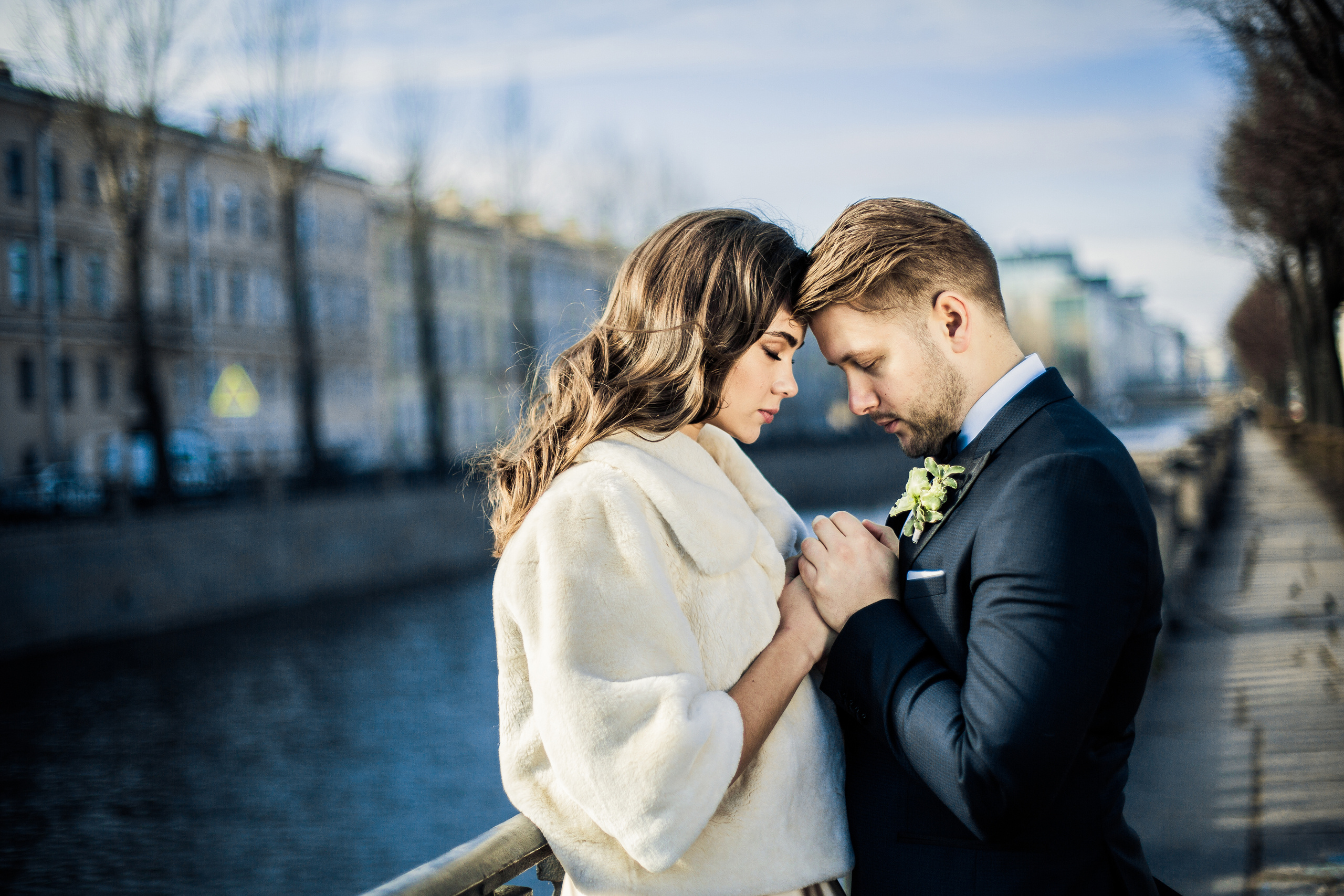 жених держит нежные ладони невесты на осенней набережной