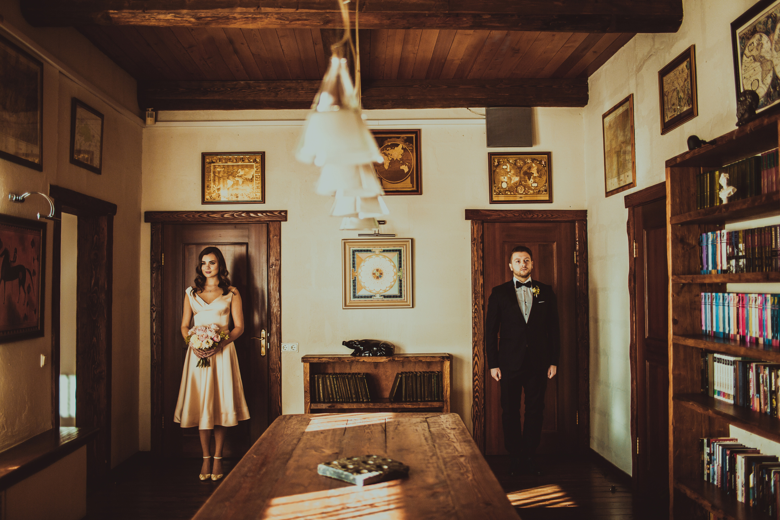 жених и невеста стоят у дверей в интерьере комнаты с деревянной отделкой