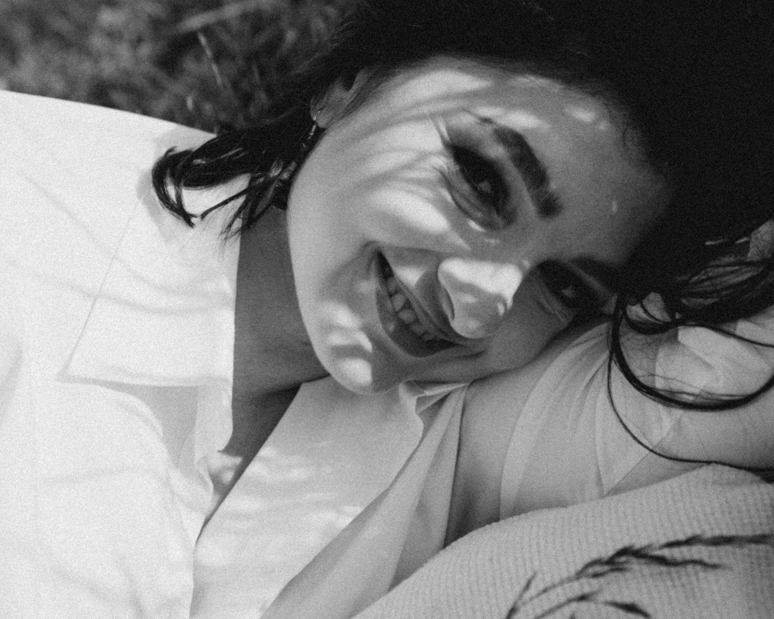 Черно-белый крупный портрет девушки с красивыми тенями травы. Красивая девушка в белой рубашке.