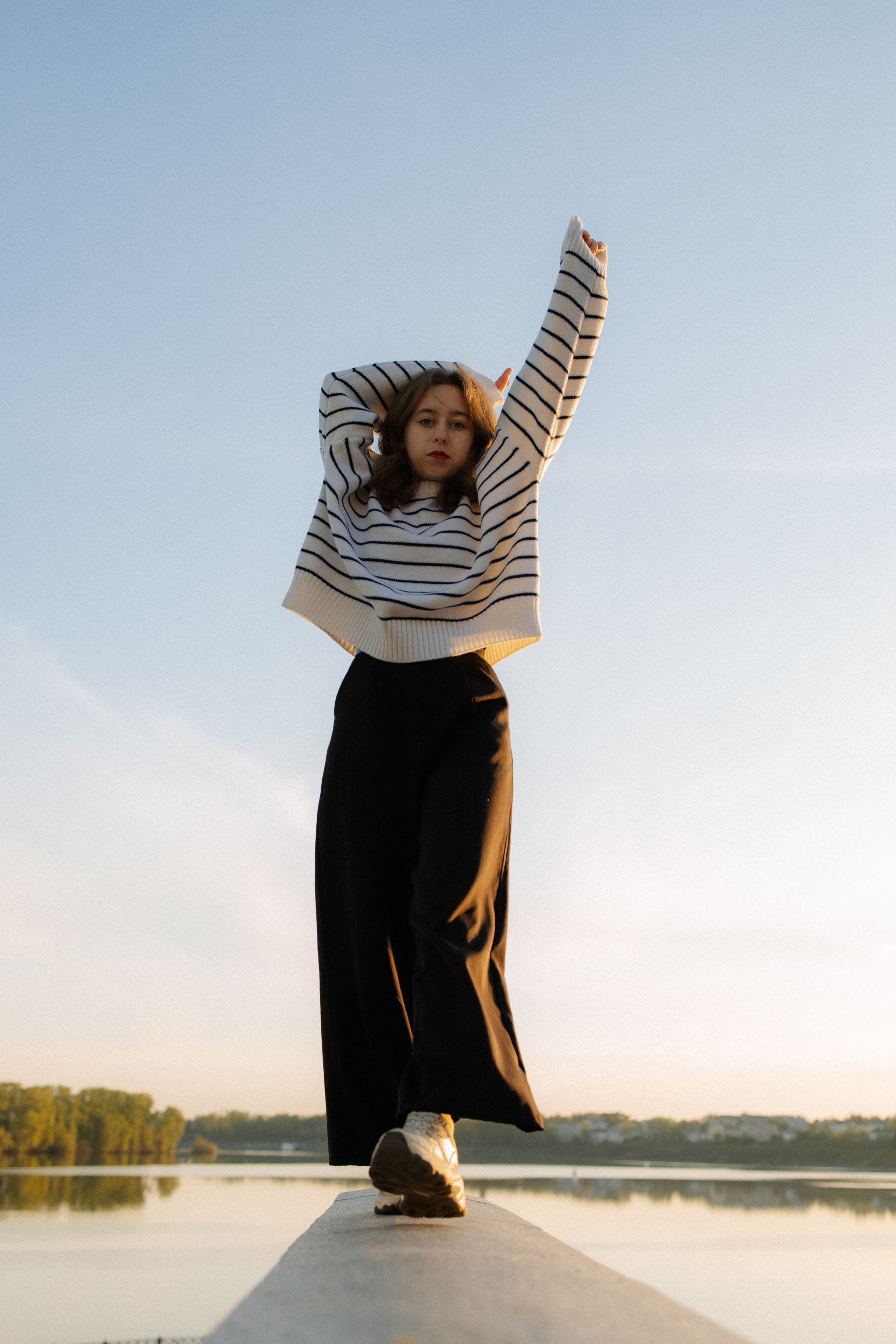 Фотография девушки в полный рост на фоне яркого голубого неба. 