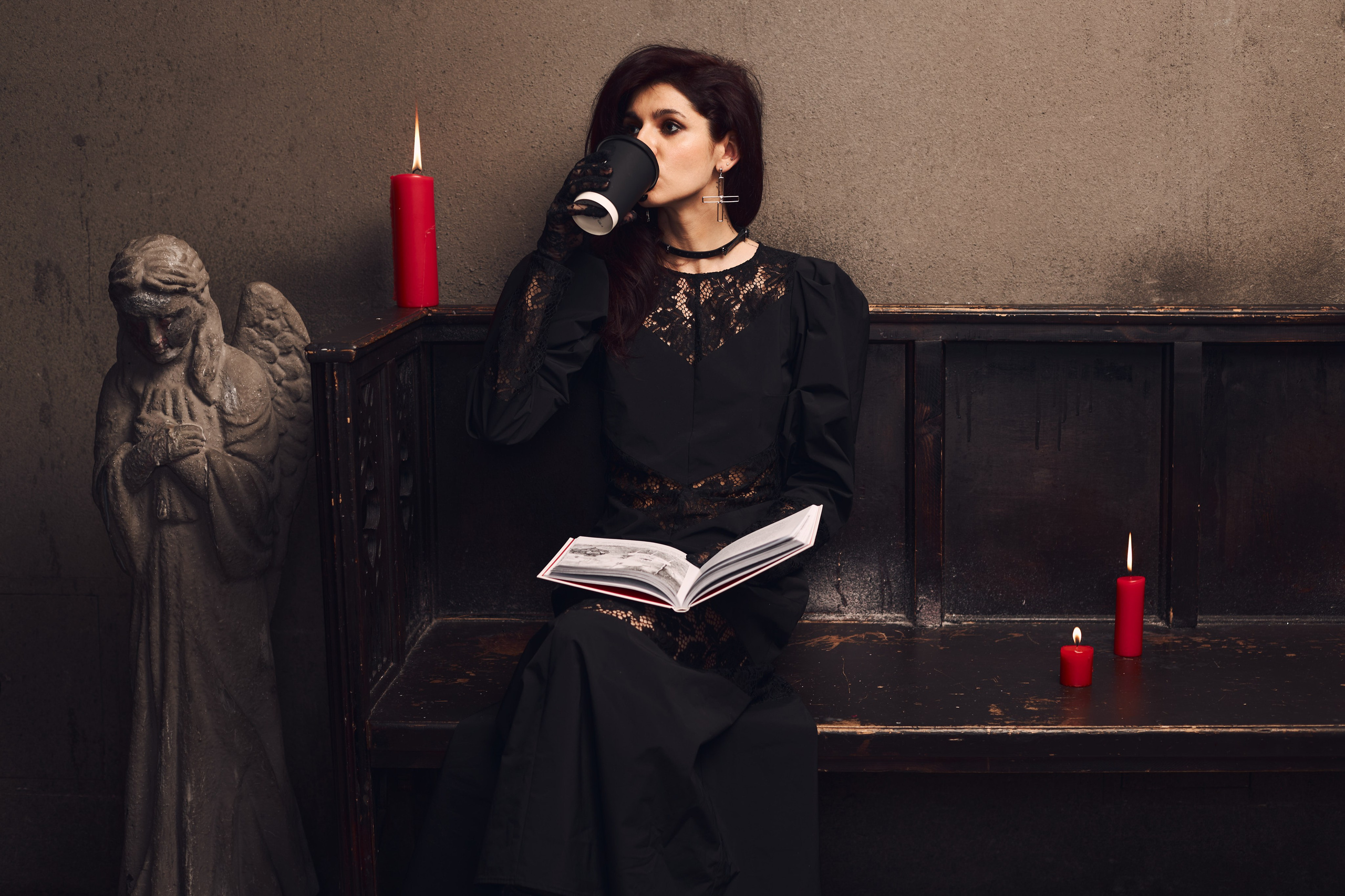 Девушка в платье сидит на скамье и читает книгу