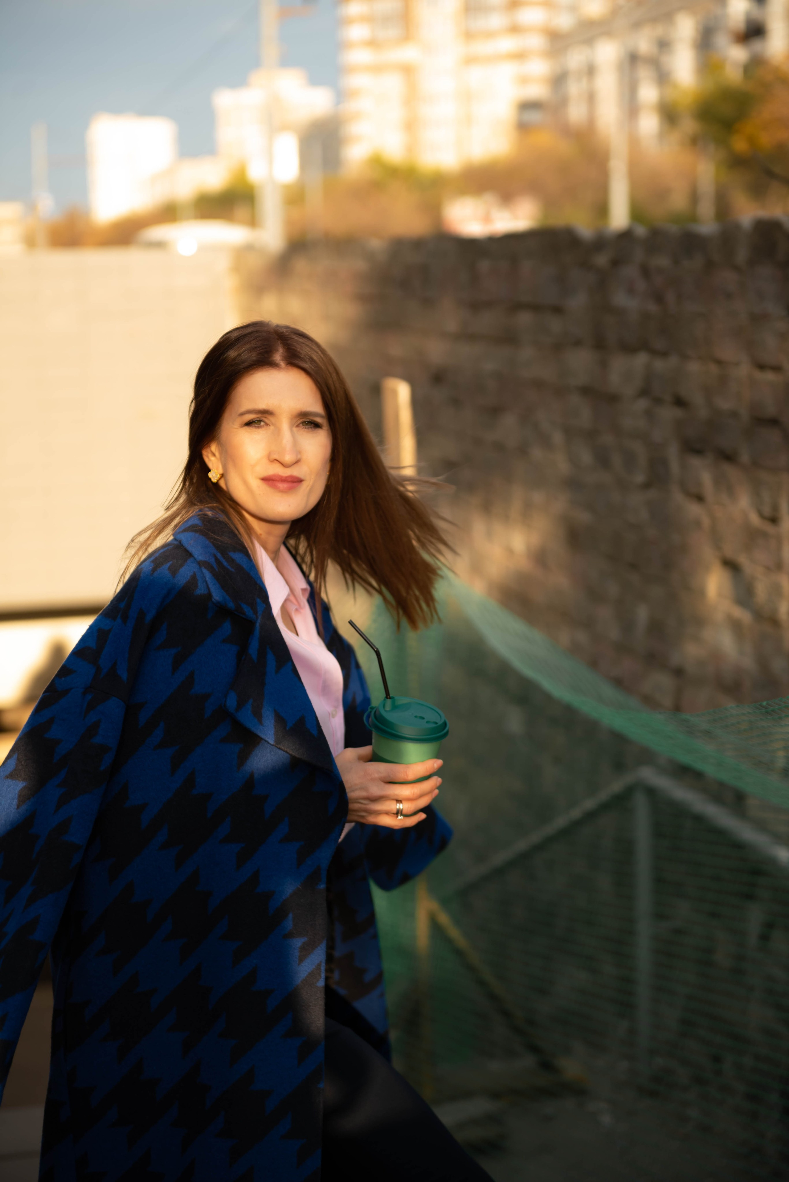 Деловая женщина в подземном переходе со стаканчиком кофе в руке.