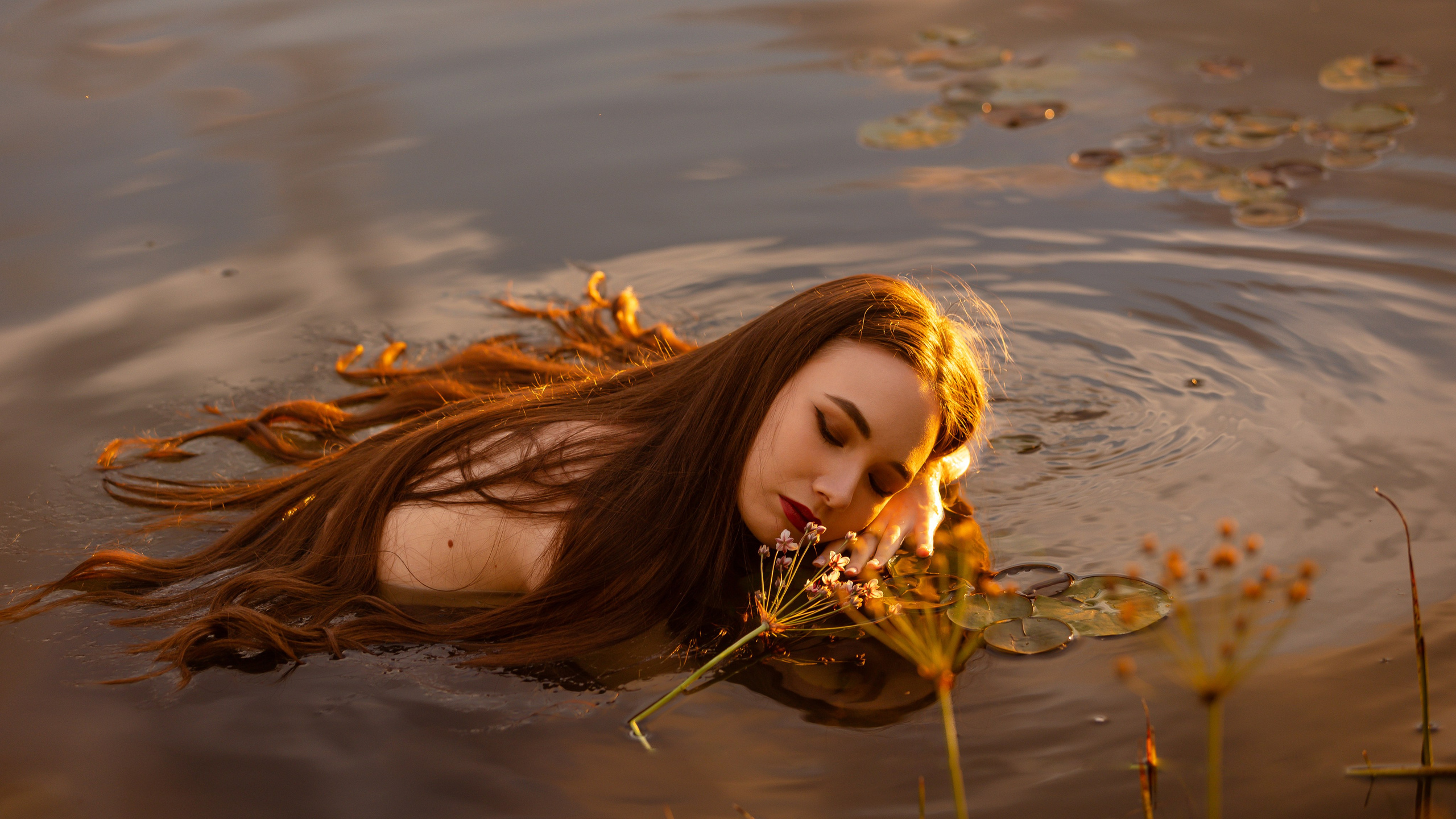 Красивая девушка плавает в пруду с кувшинками