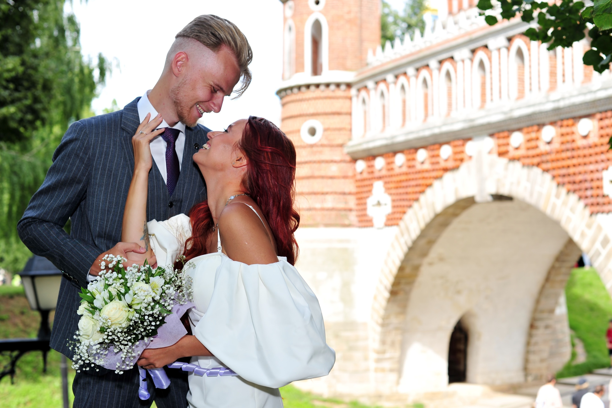 Свадьба в Царицыно летом, молодожены смотрят друг на друга на фоне моста и арки