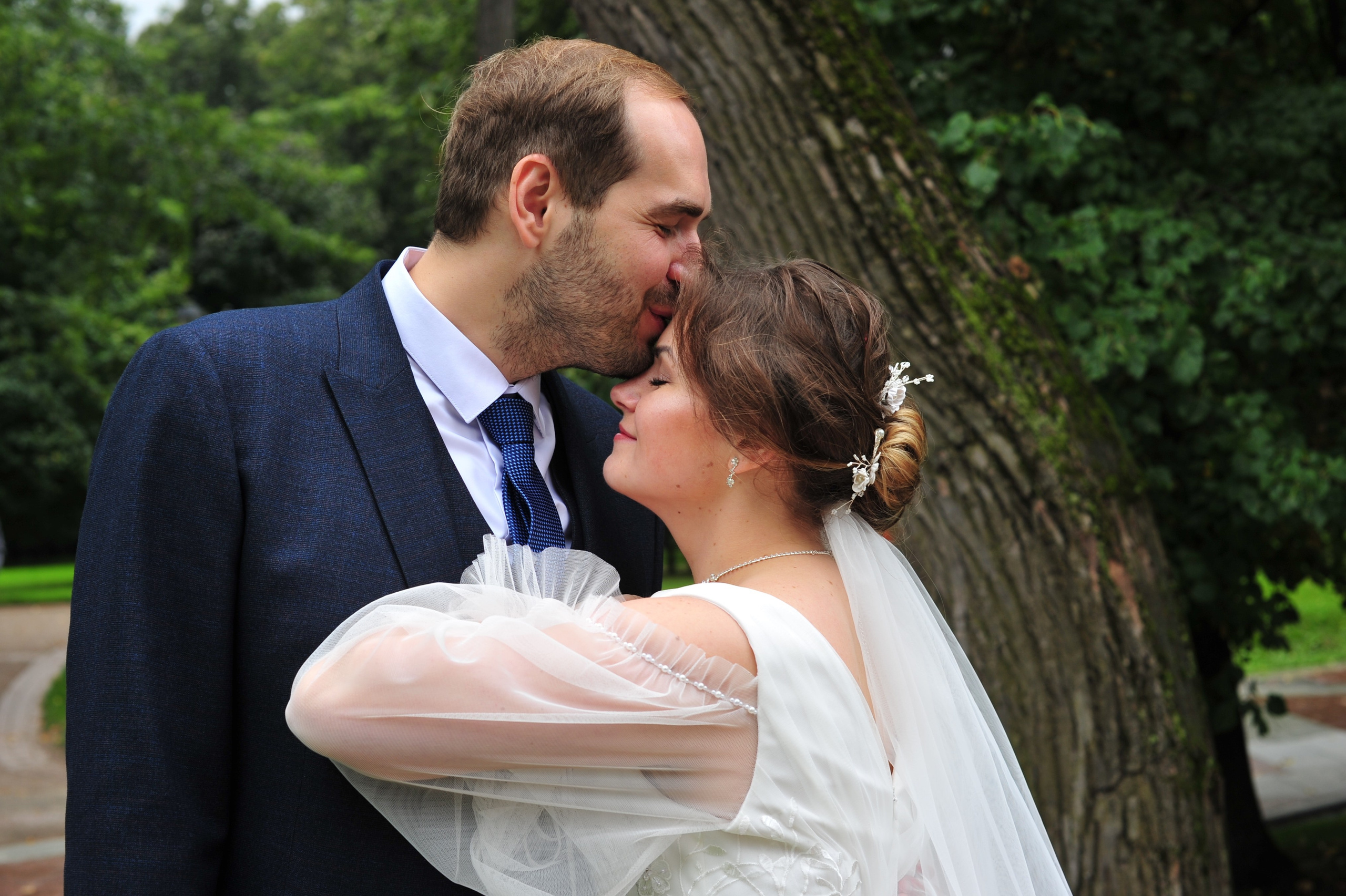 Свадьба в Царицыно пасмурным летним днем, жених целует невесту в лоб 