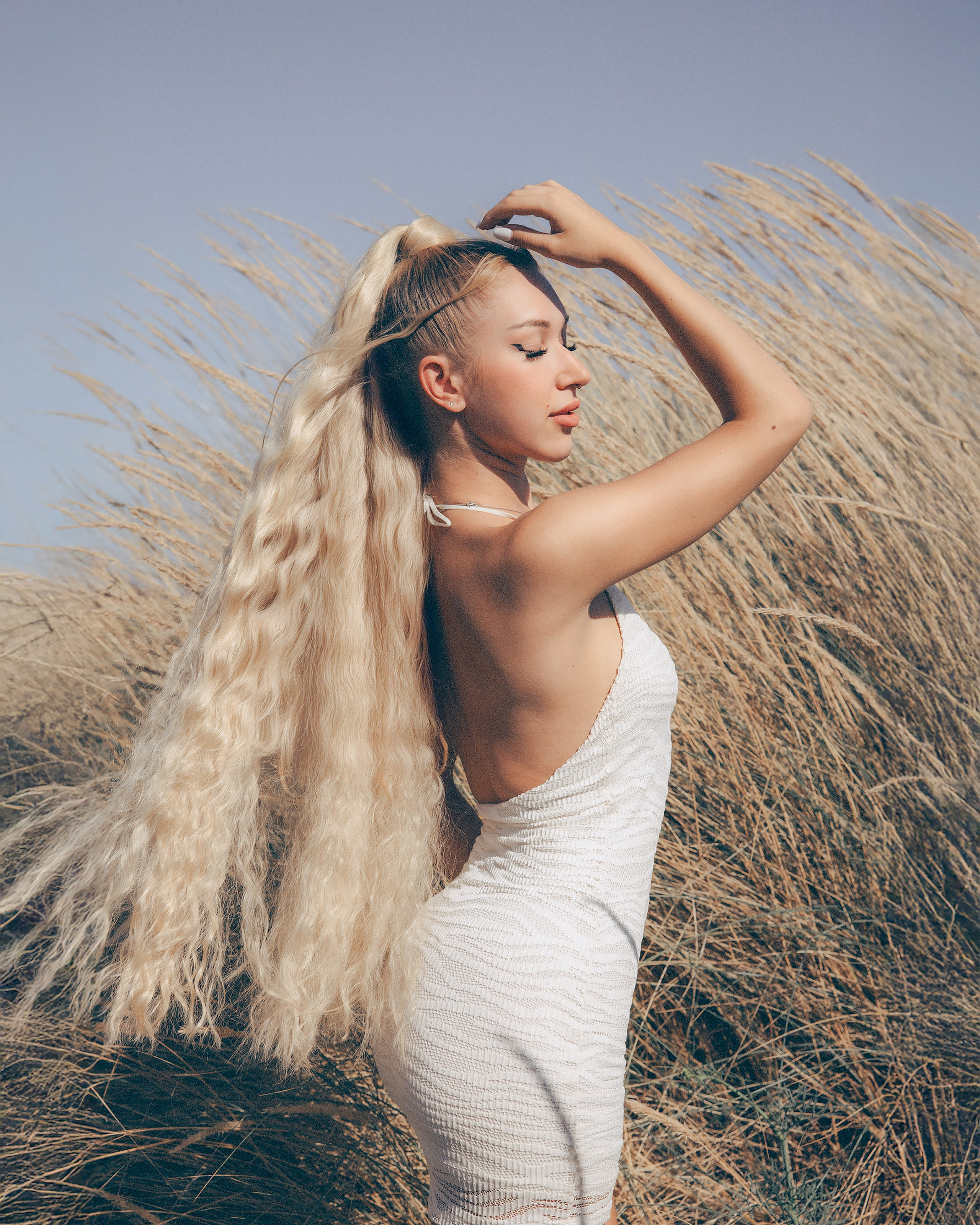 Elegant blonde woman in a flowing dress at a seaside engagement session in Barcelona.