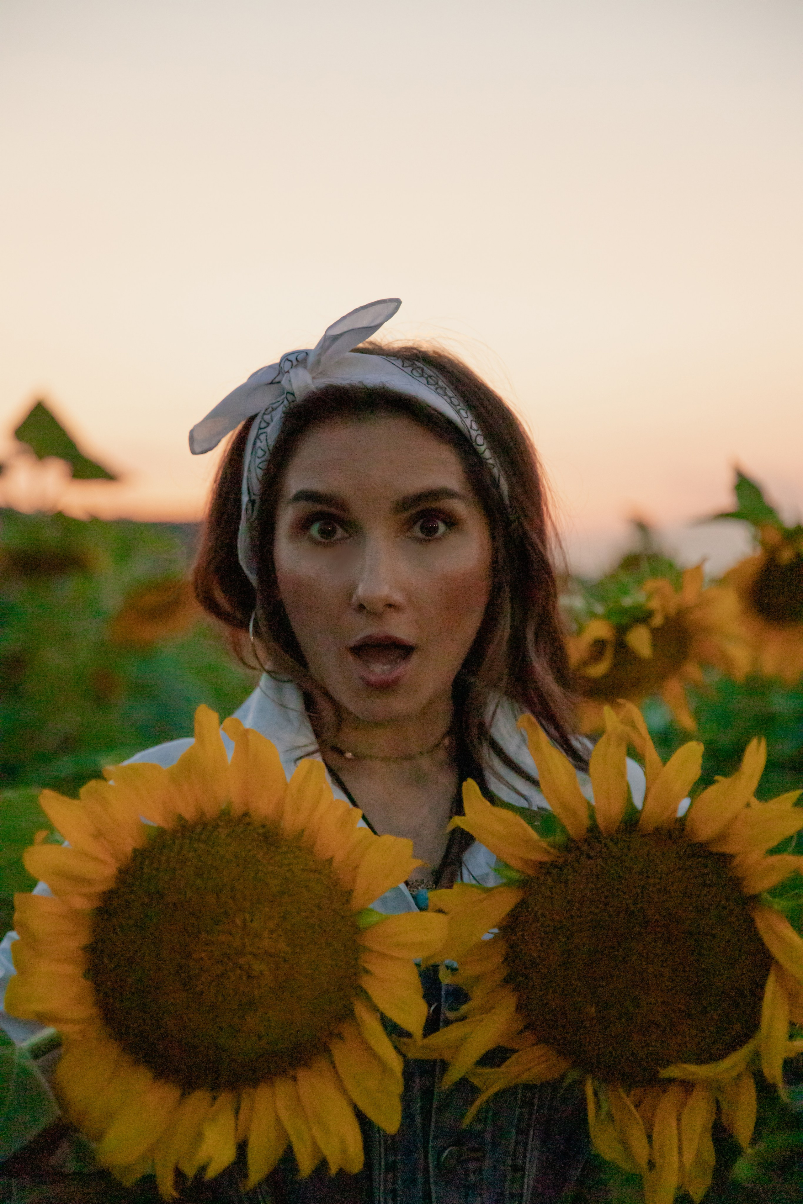 Крупный план — детские ручки, касающиеся лепестков подсолнуха, олицетворяющие простой радость природы и беззаботность