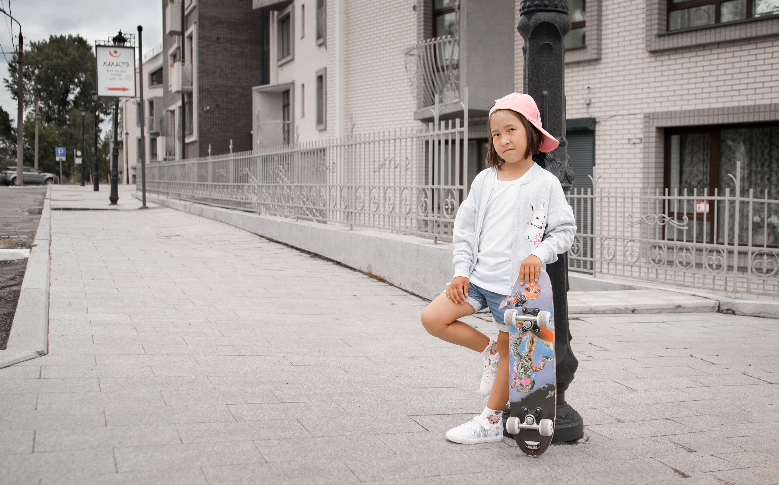 Детская фотосессия летом - девочка стоя в бейсболке у фонарного столба