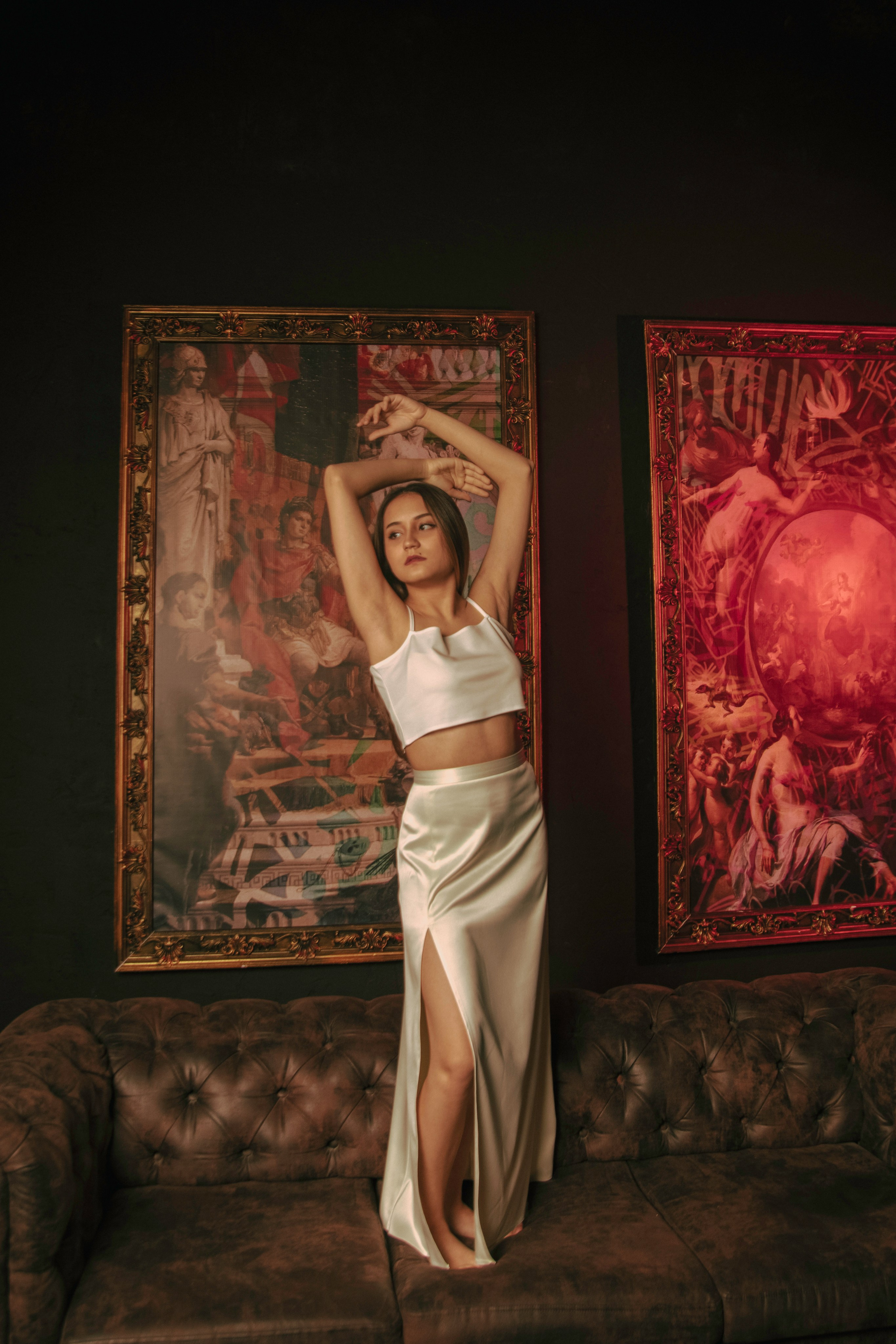 Девушка фотографируется в стиле ренессанса в белом платье на фоне картин