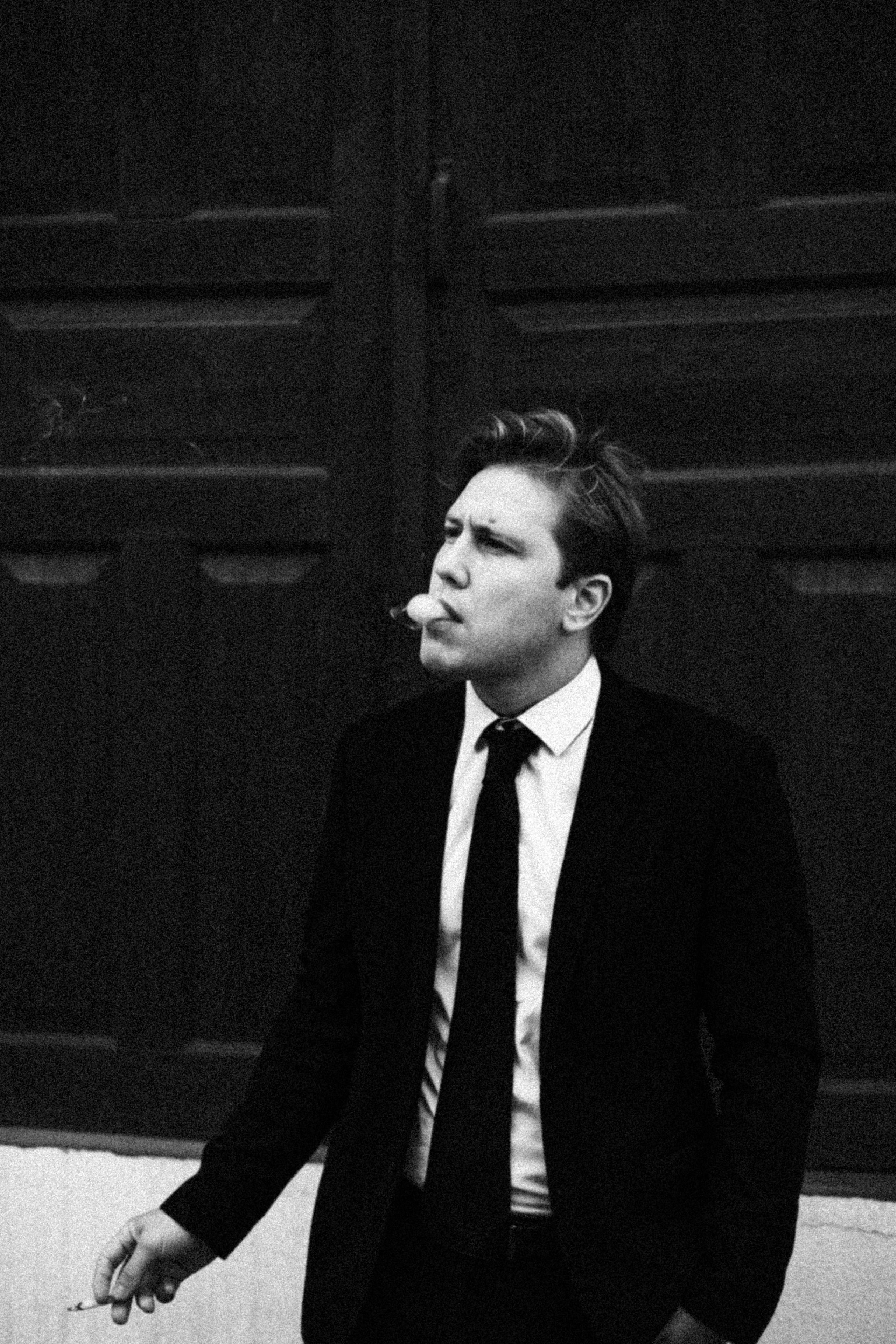 Мужчина в костюме курит у двери