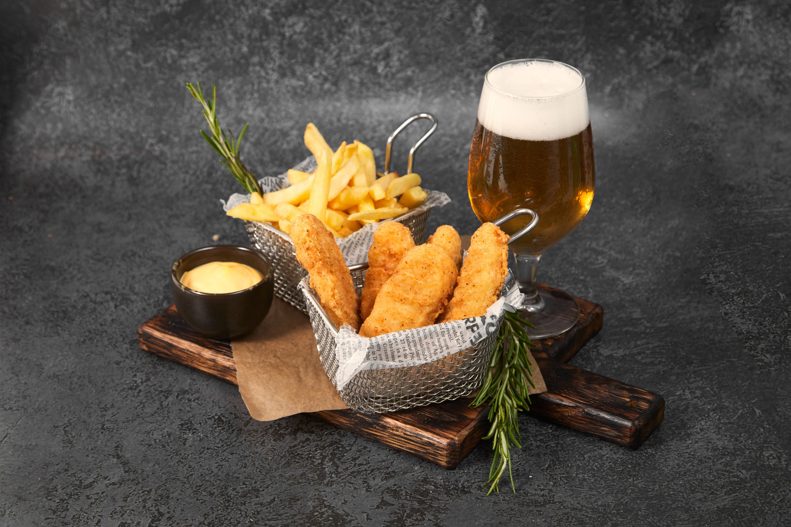 Картофель фри в корзинке с пивом на фоне.
