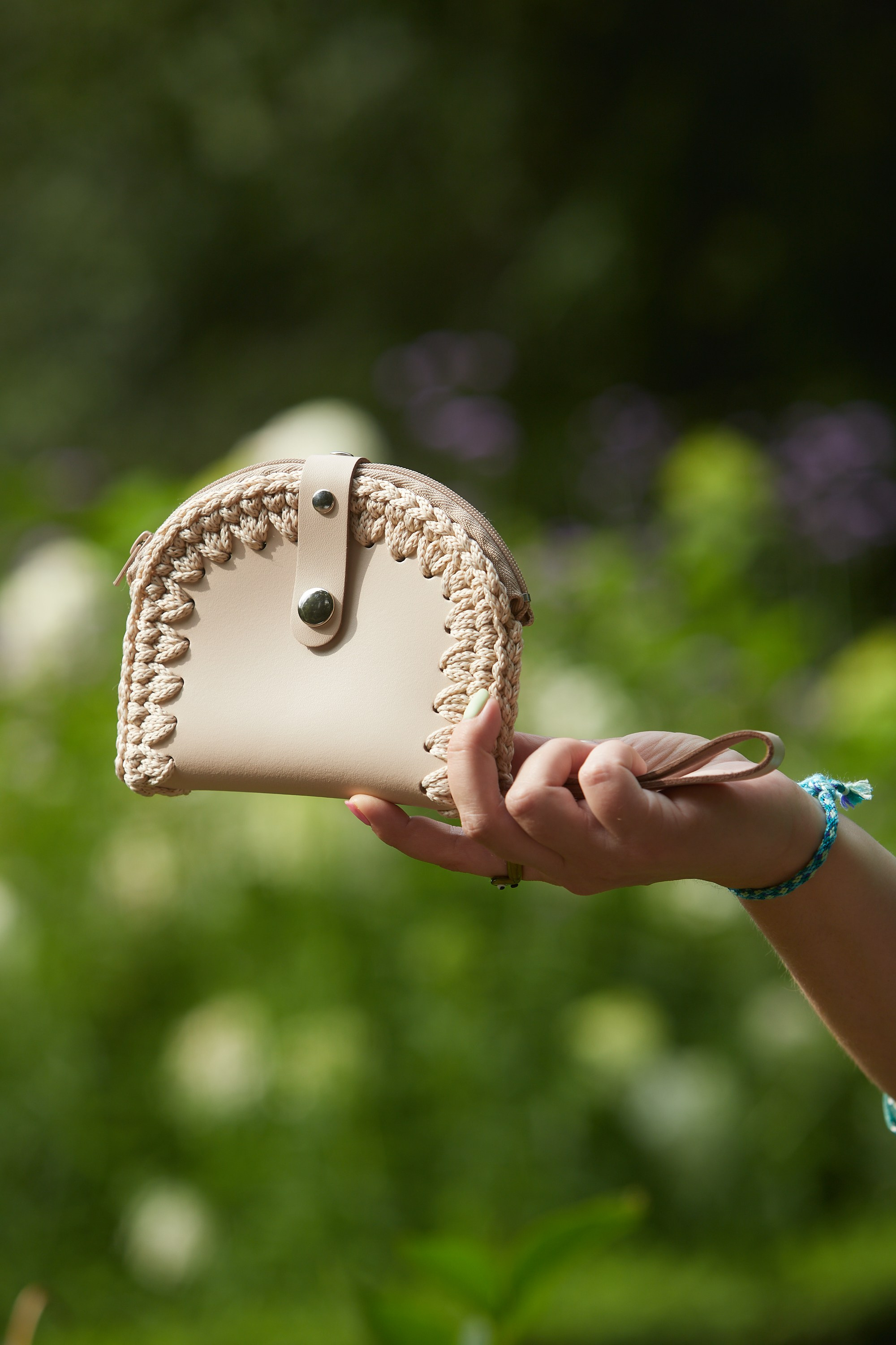 Предметная съёмка — бежевая вязаная сумка с деревянными ручками на траве.