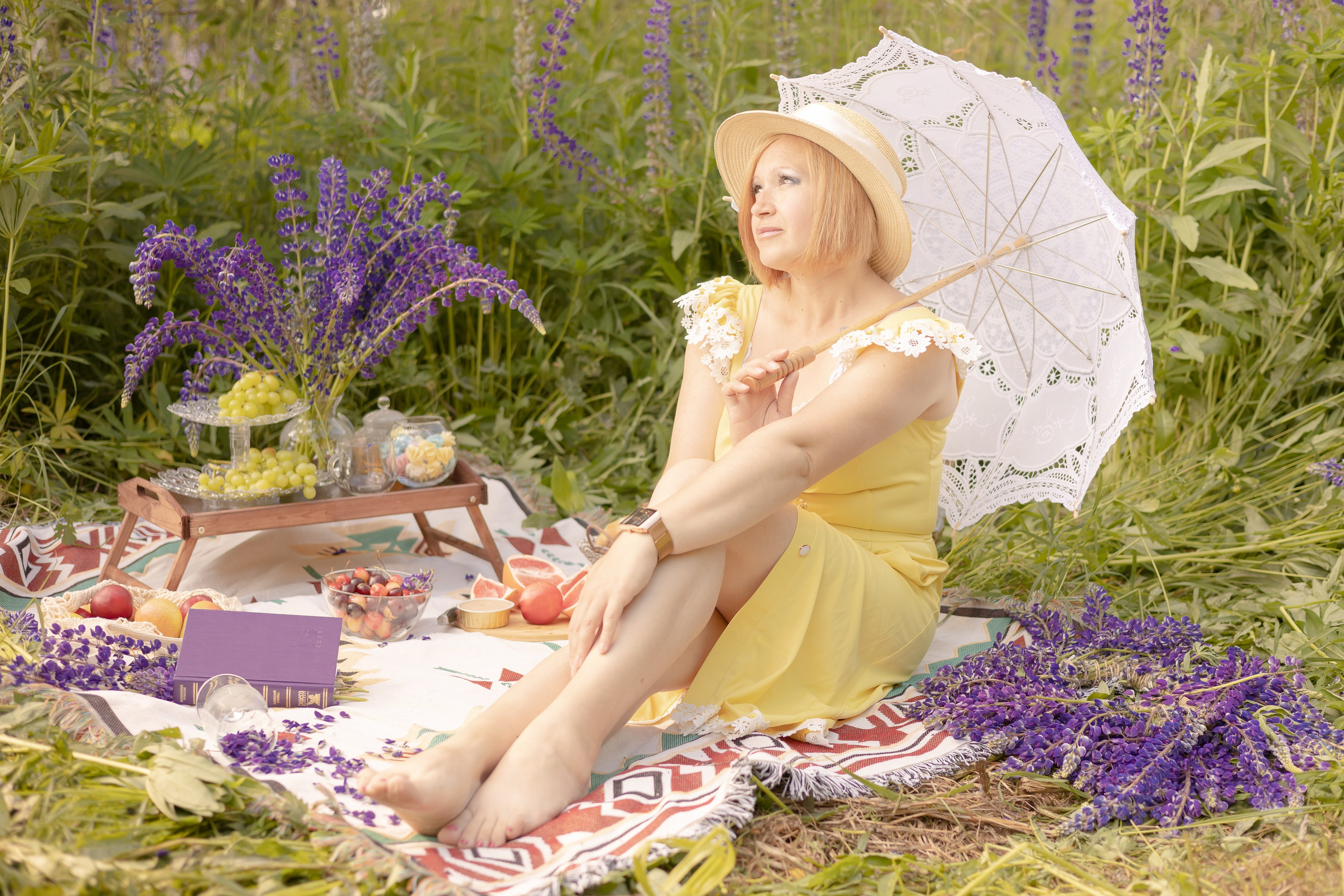 Люпиновое поле. Девушка сидит на узорном пледе, прячется от солнца под кружевным зонтом.