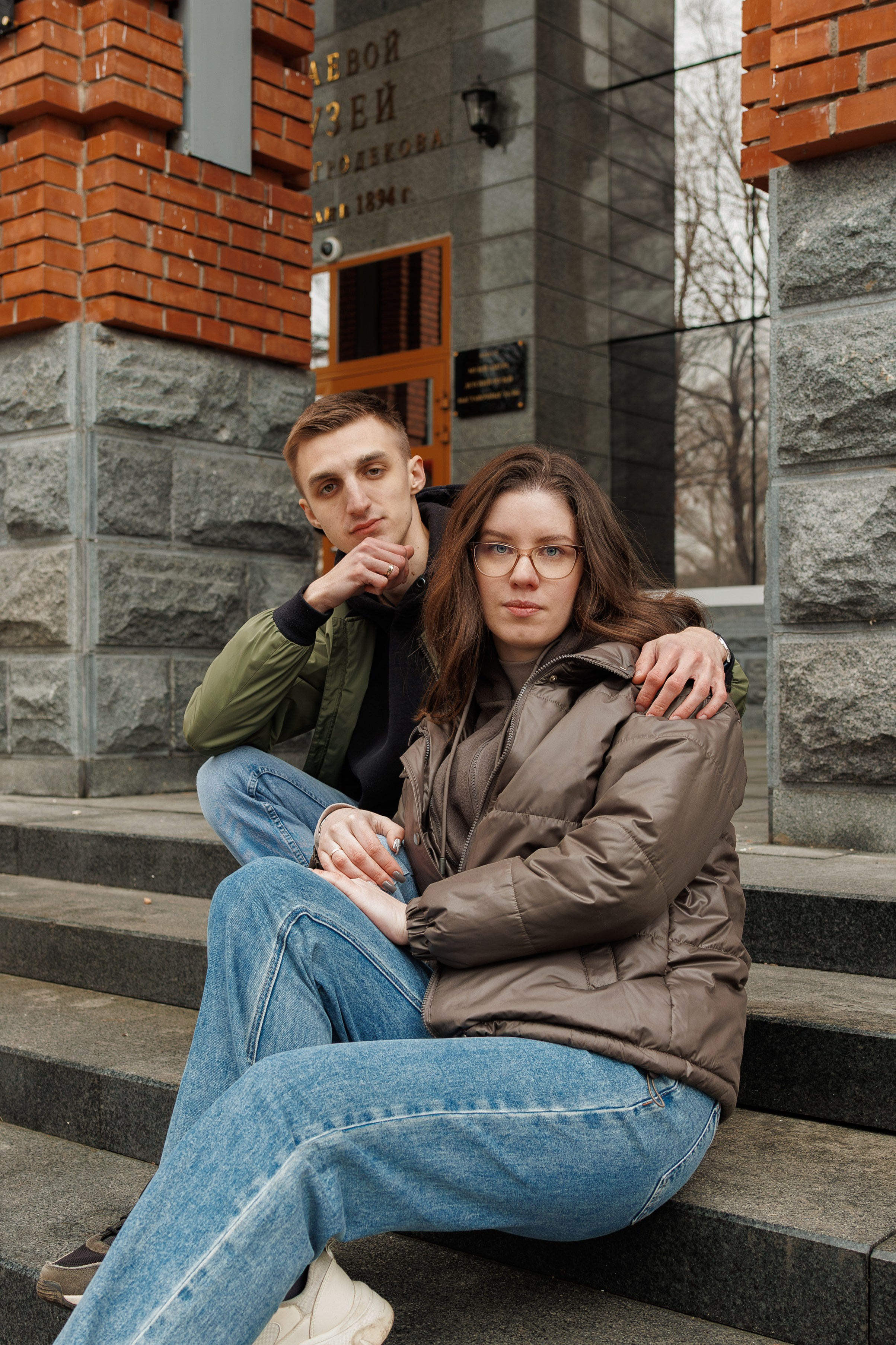 Прогулочная фотосессия в Хабаровске у Гродековского музея. Пара сидит на гранитных ступенях исторического здания, профессиональная уличная съемка