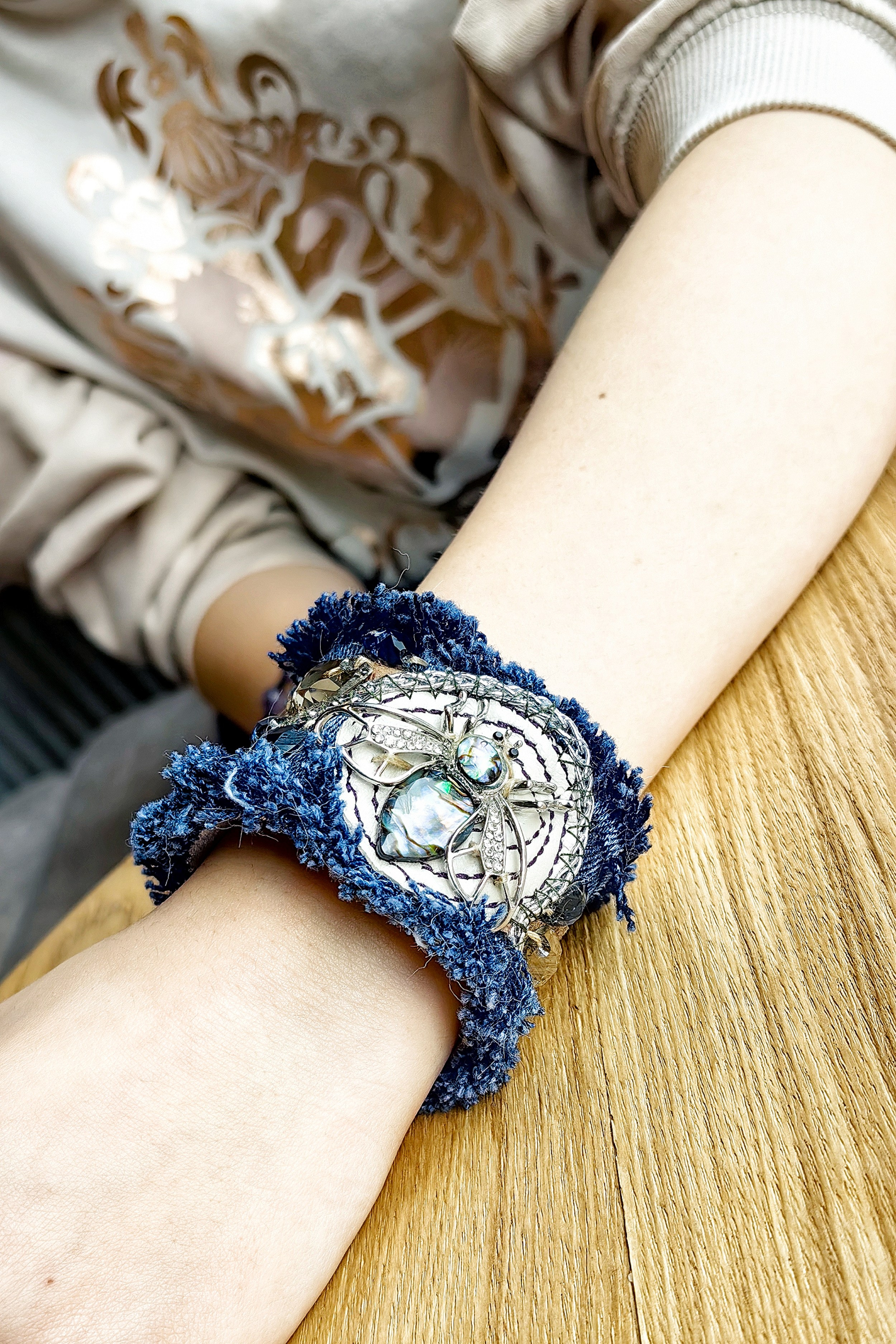 Девушка демонстрирует браслет из джинсы с оригинальной фурнитурой в стиле ар-деко, который сшила сама и украсила.