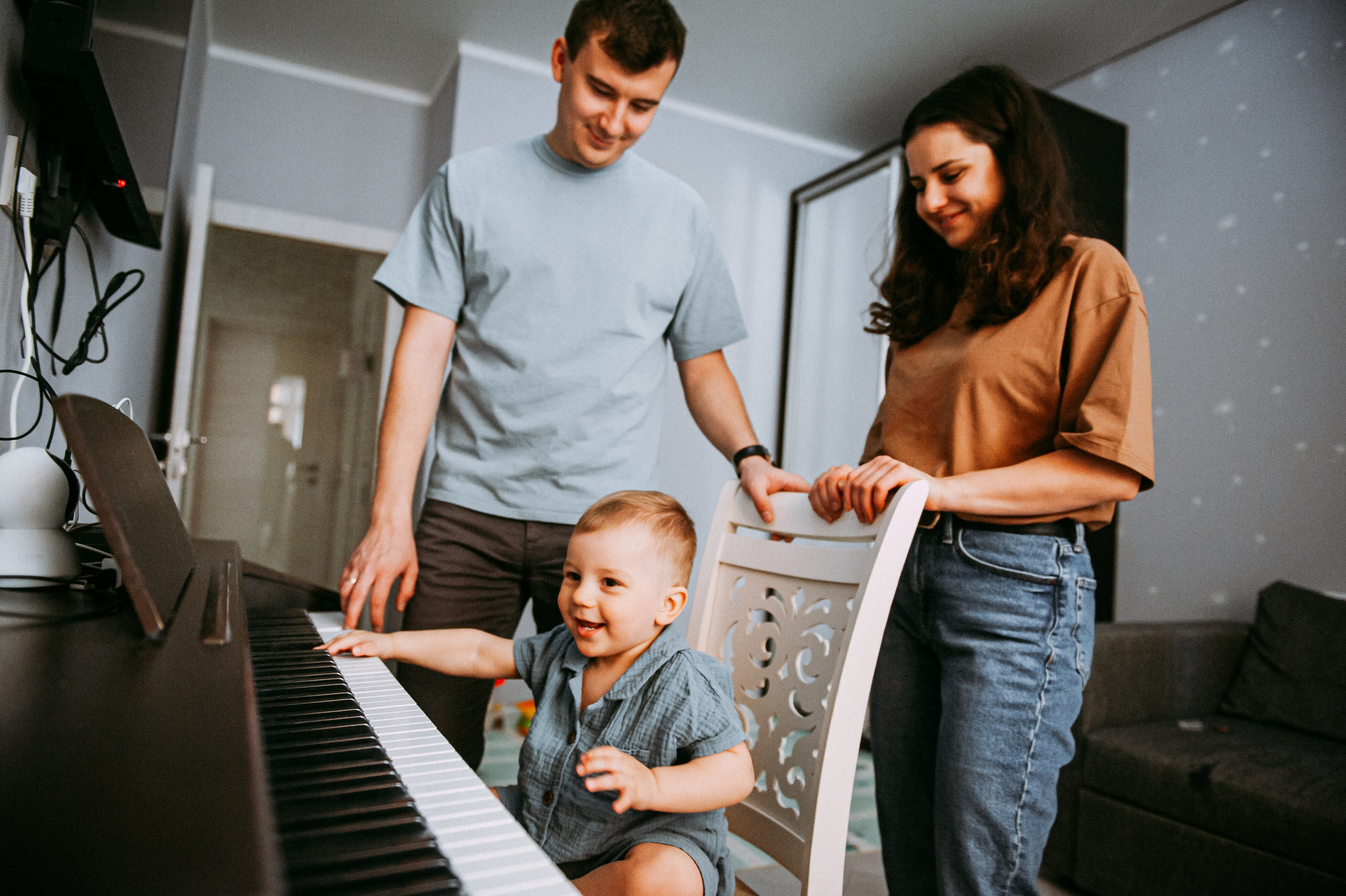 родителя смотрят как ребенок играет на пианино