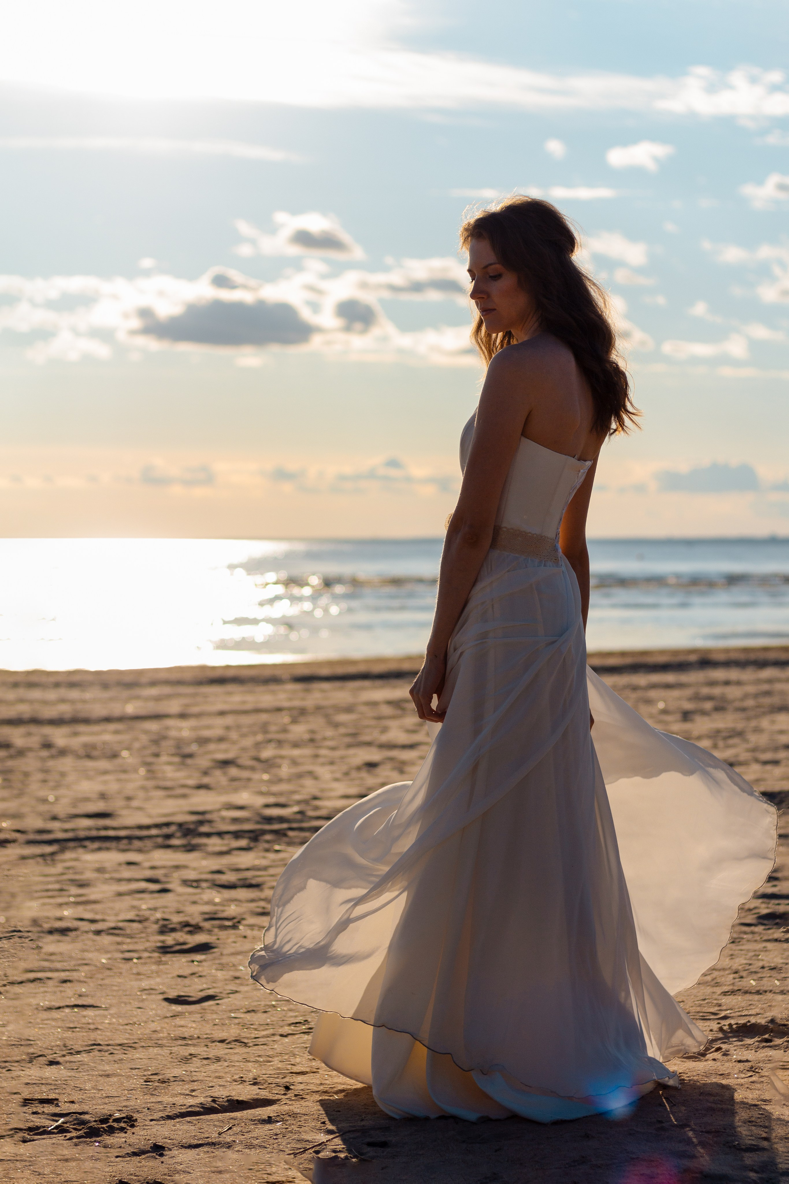 Девушка на берегу залива со спины. Фото со спины. Фото с лучами солнца. Фотографии с бликами на воде.