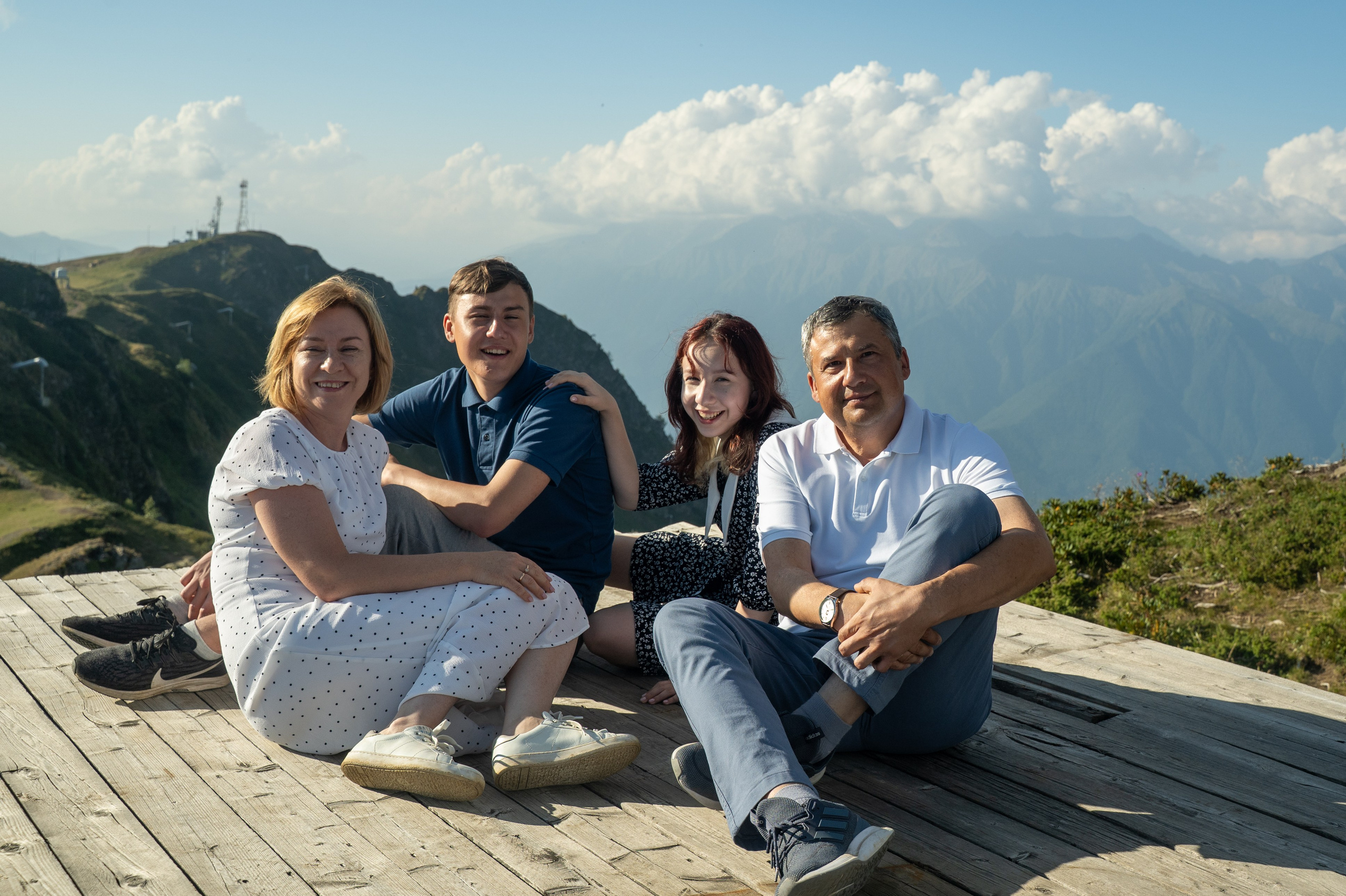 Фотоснимок детей и родителей на фоне гор на смотровой площадке 