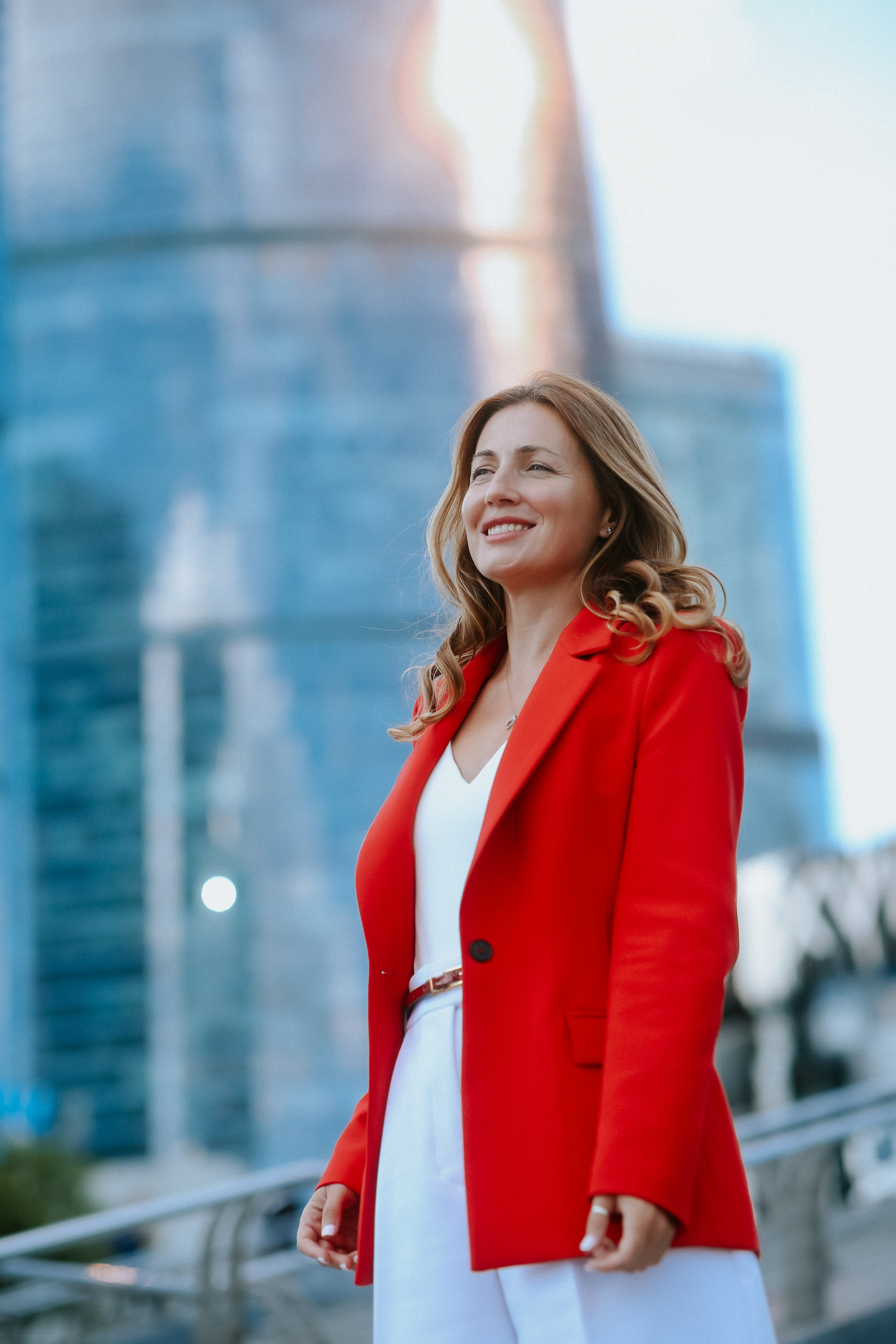 <img src="IZ0A0352.jpg" alt="Красивая девушка в в ярком красном пиджаке улыбается и позирует на фоне небоскрёбов Москва-Сити">