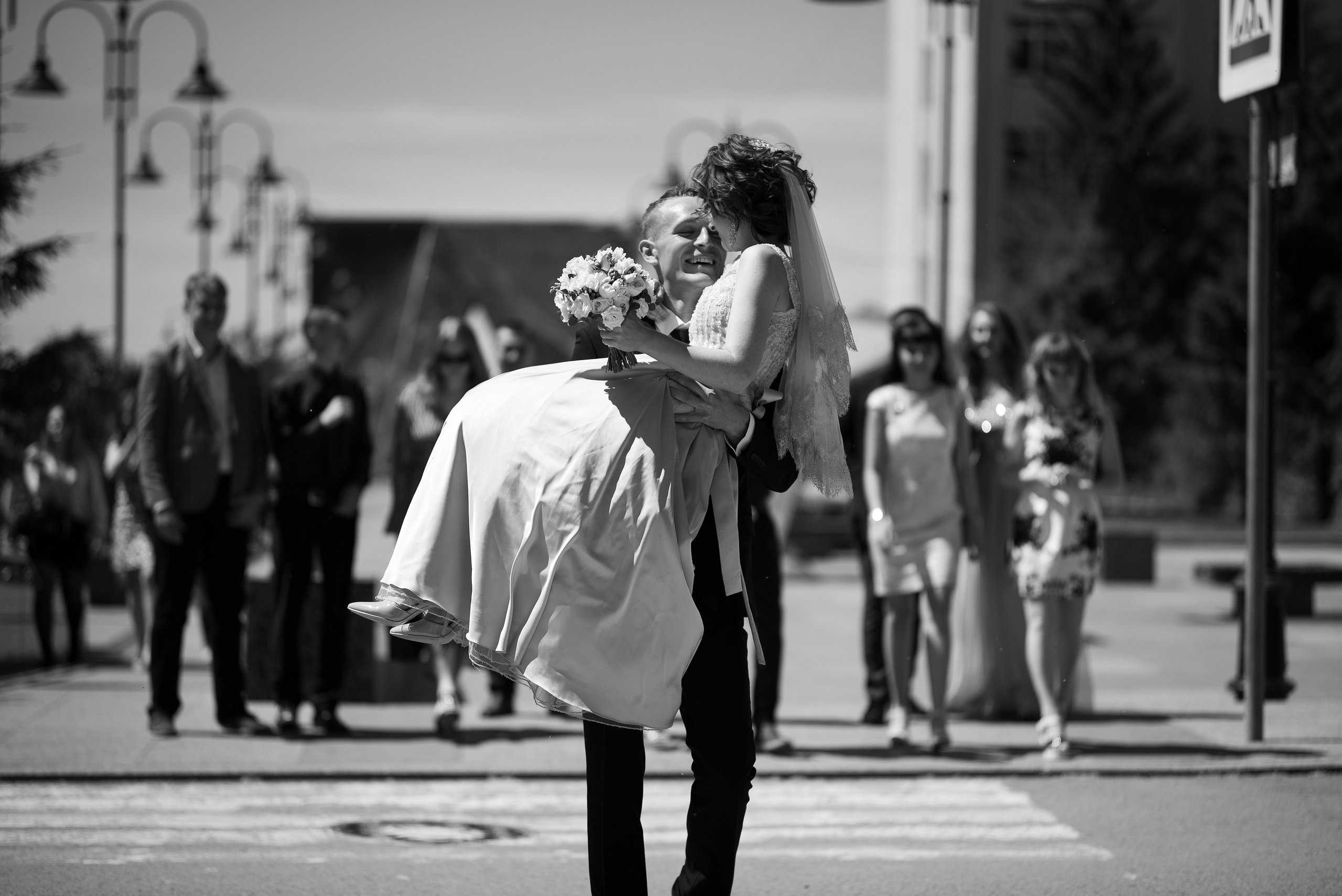 Жених переносит невесту через дорогу.