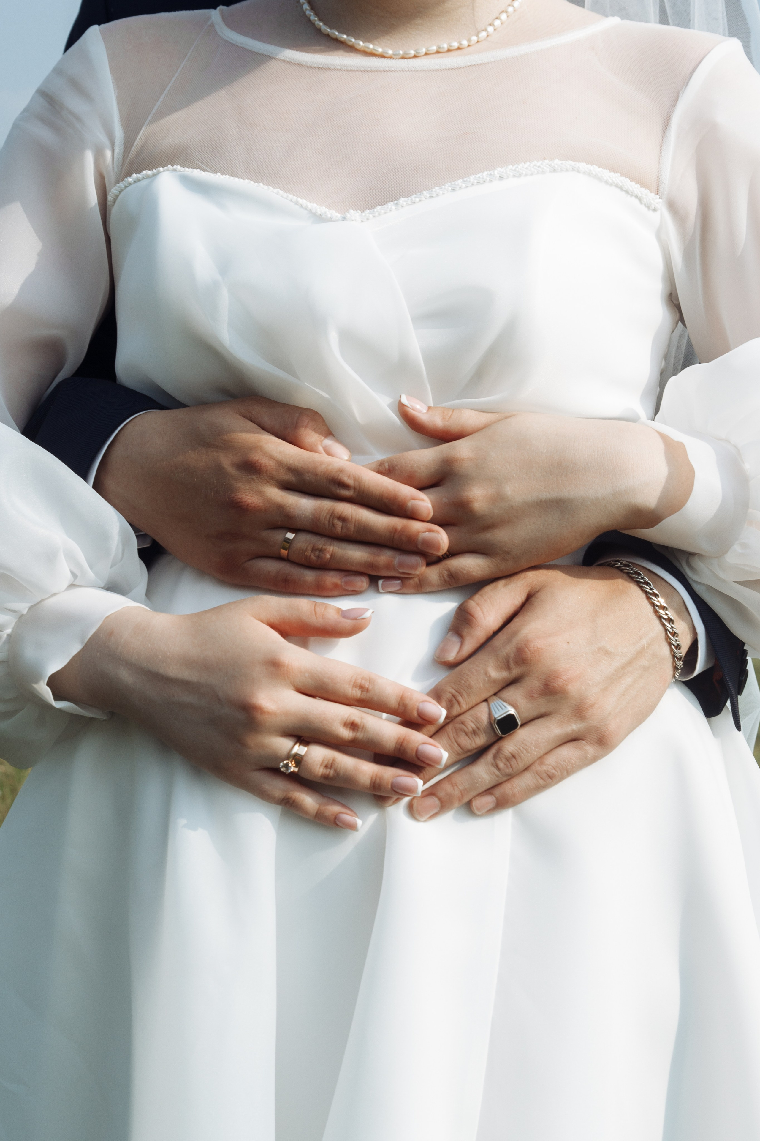  Крупный план рук жениха и невесты, лежащих друг на друге — обручальные кольца и прикосновения.