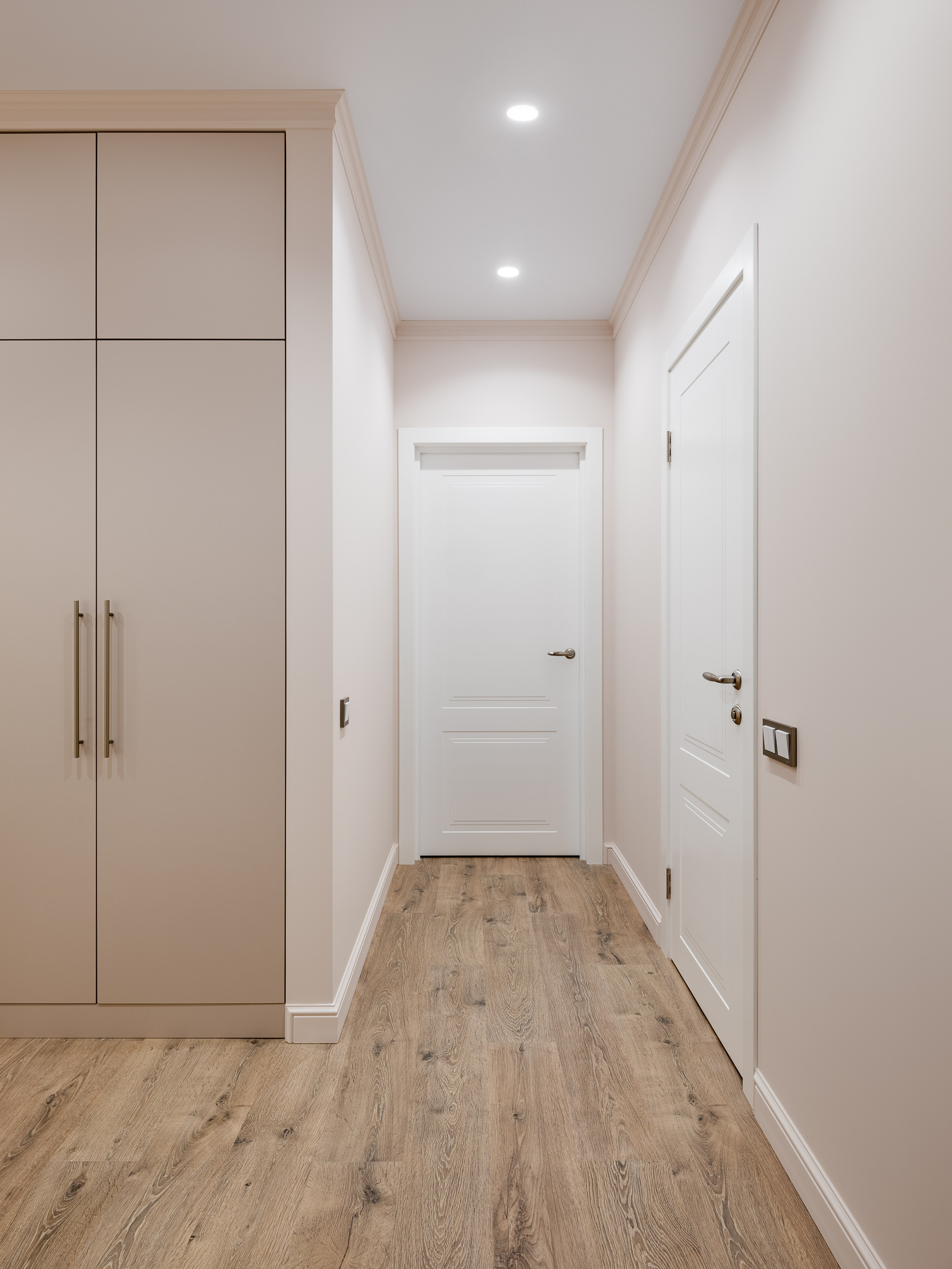 Светлый коридор с белыми дверями, встроенными шкафами и деревянным напольным покрытием в современном стиле минимализм. Дизайн пространства Наталья Бунеева, стилистическая подача Наталья Якушева, фотография Сергей Денисенко.