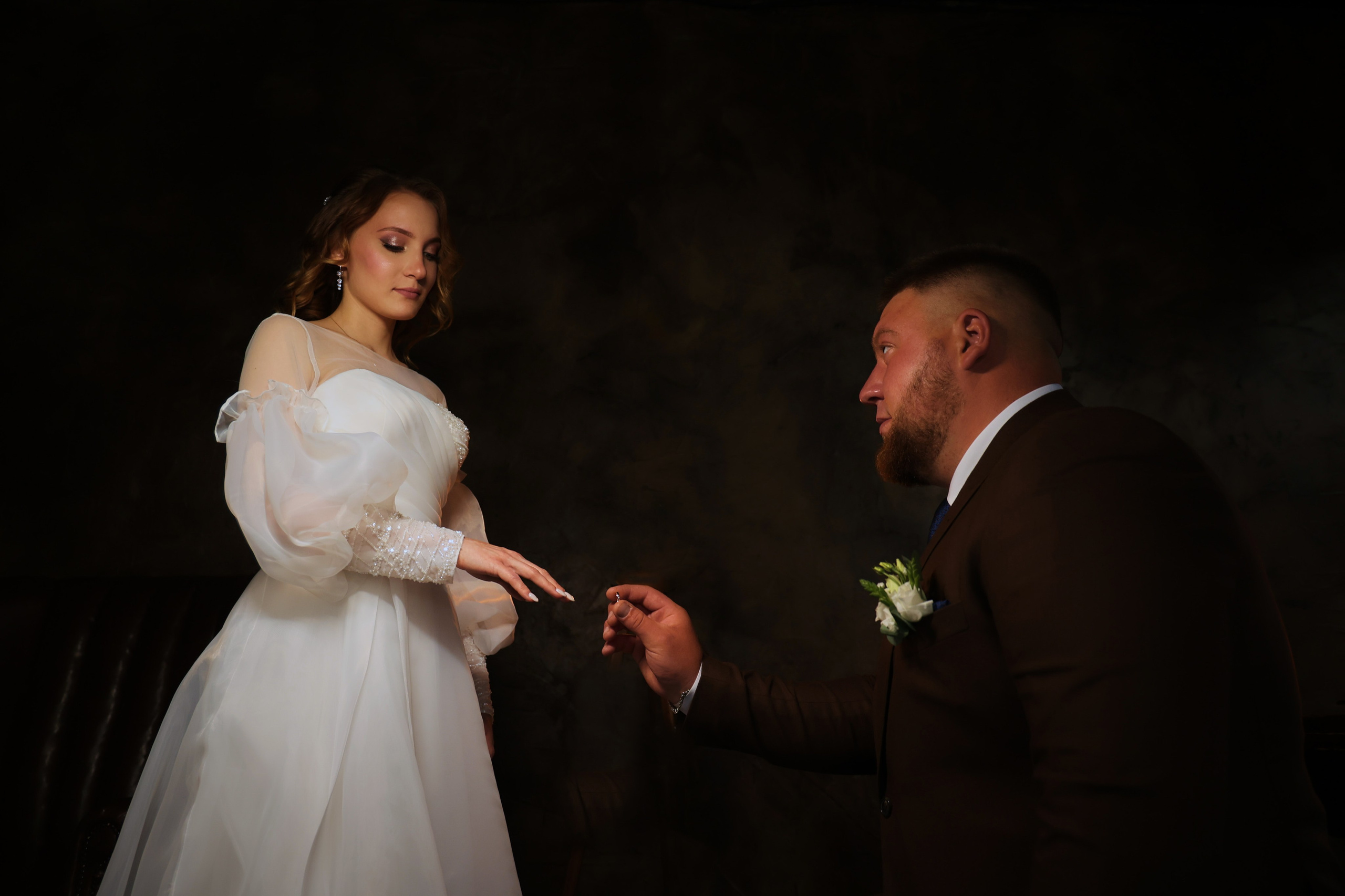 жених одевает свадебное кольцо в фотостудии