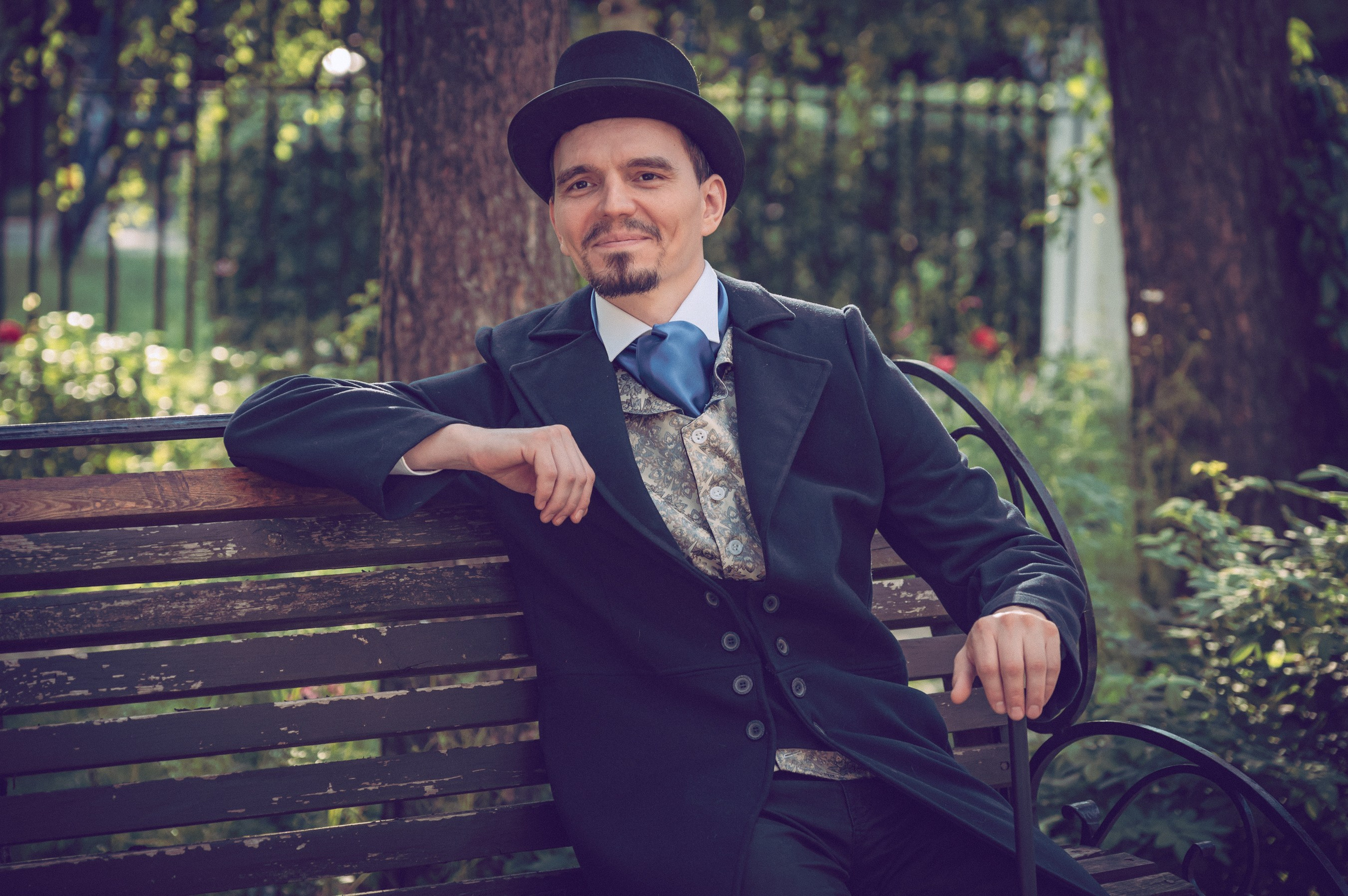 мужчина сидит на скамейке в цилиндре с тростью