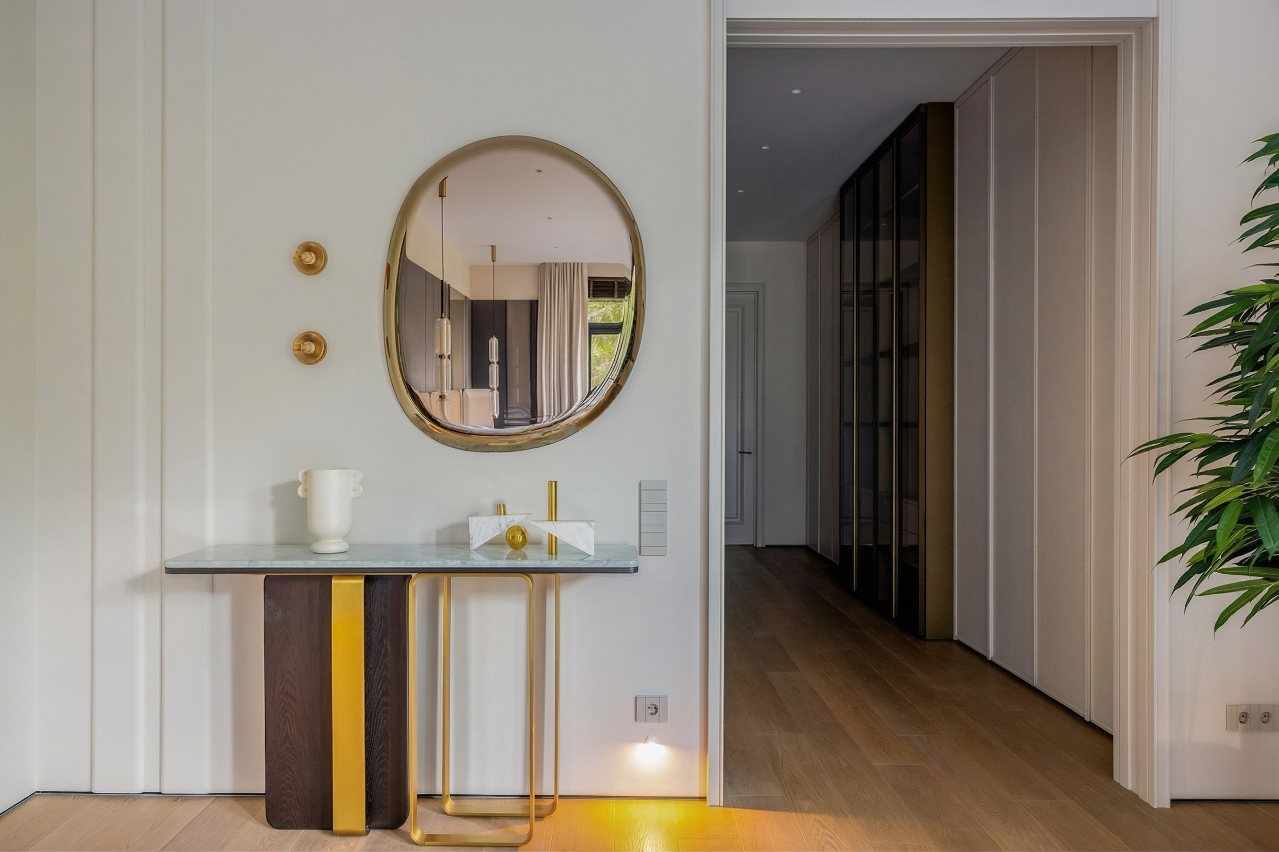 Интерьер входной зоны мастер-спальни с дизайнерской консолью, зеркалом органической формы и встроенными гардеробными системами, проект Валерии Котович.