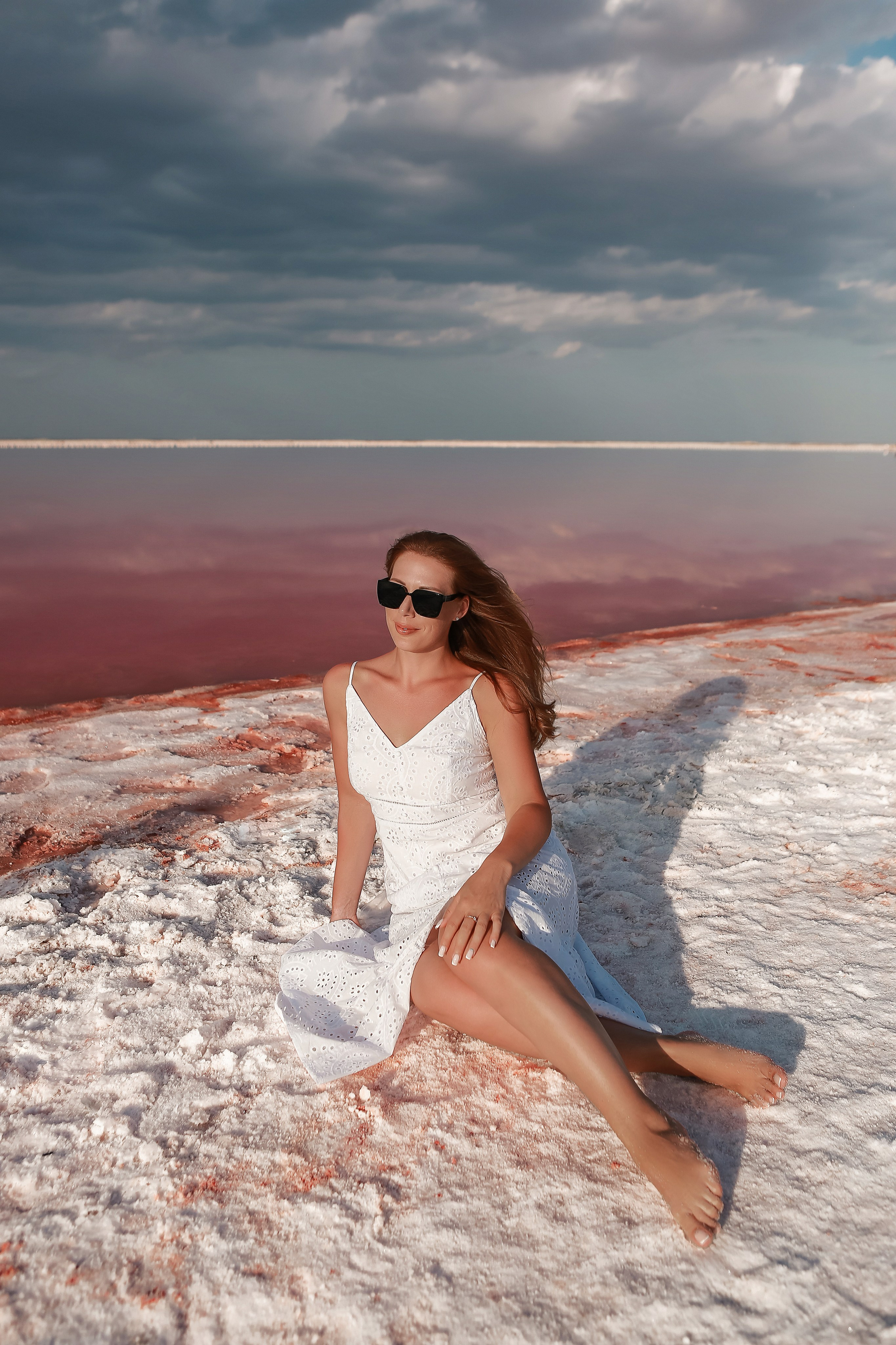 Девушка сидит на соленом берегу розового озера в Крыму