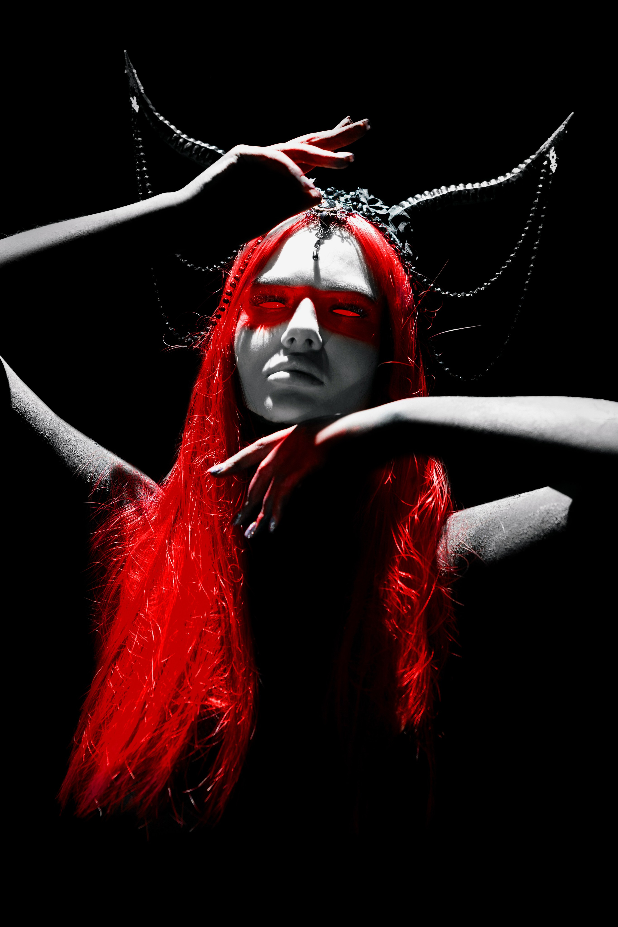 Студийный портрет девушки с красными волосами и рогами в стиле фэнтези.