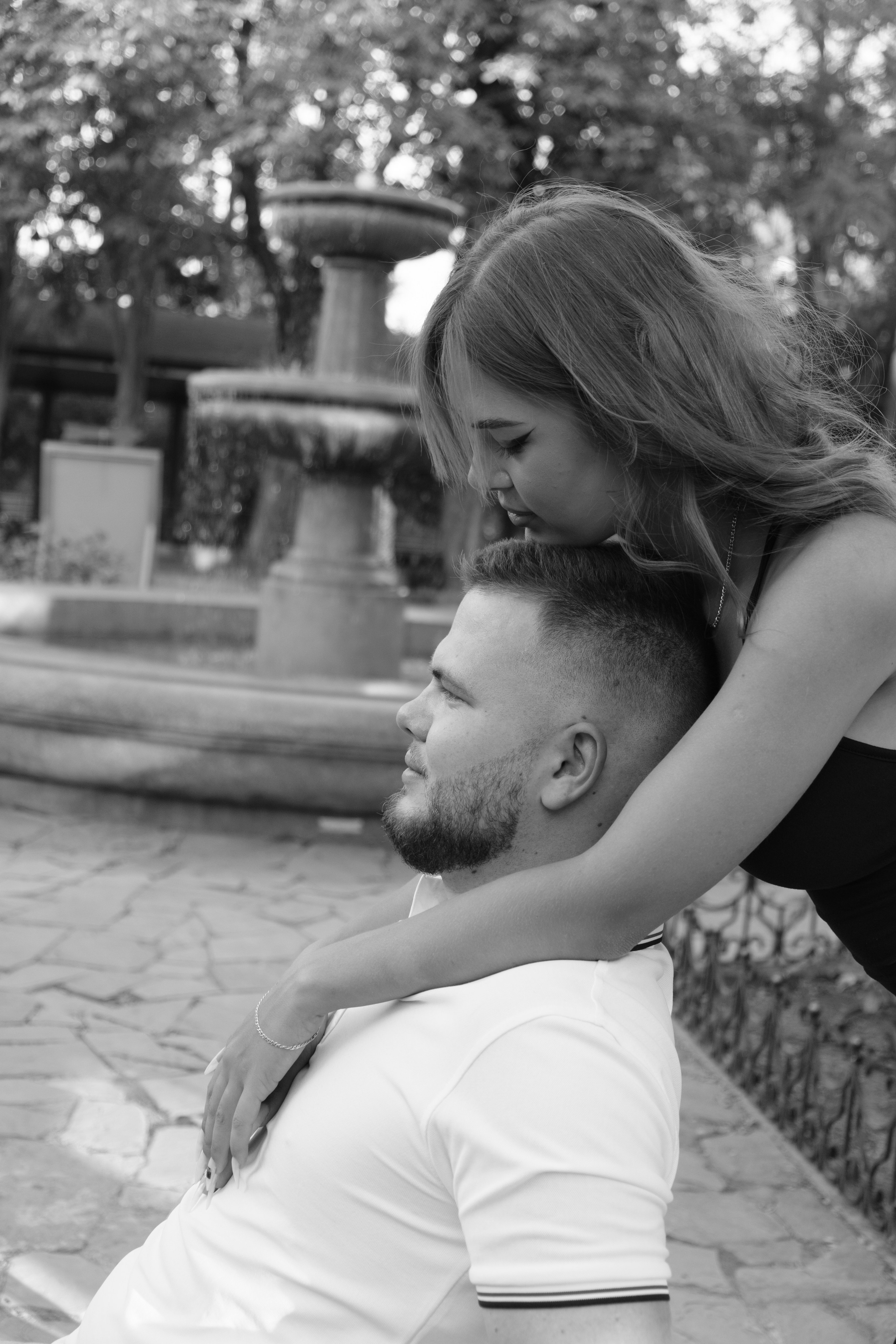 Чёрно-белая фотография где парень сидит а девушка обнимает его сзади