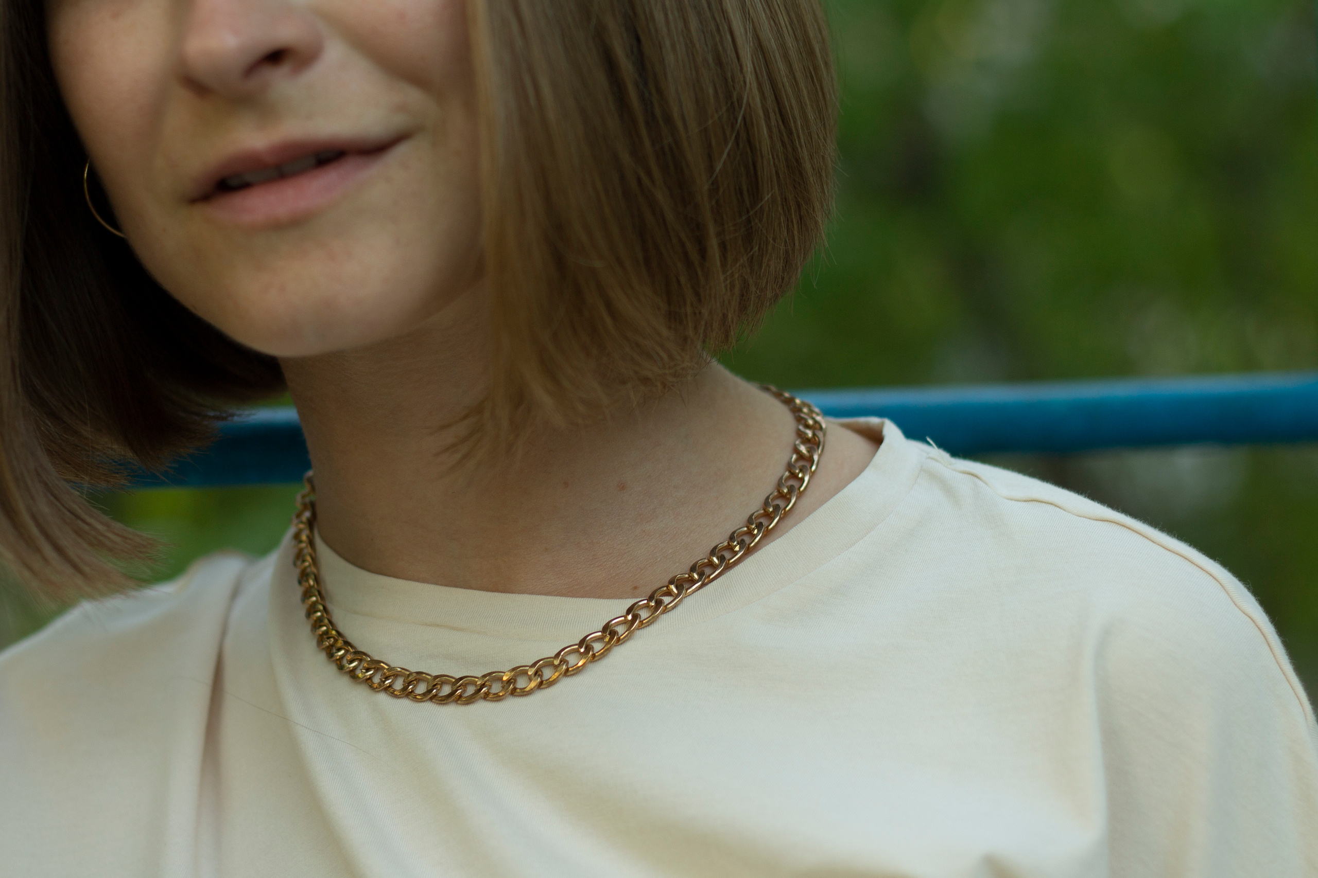 шея и плечи девушки в светлой футболке с массивной цепью