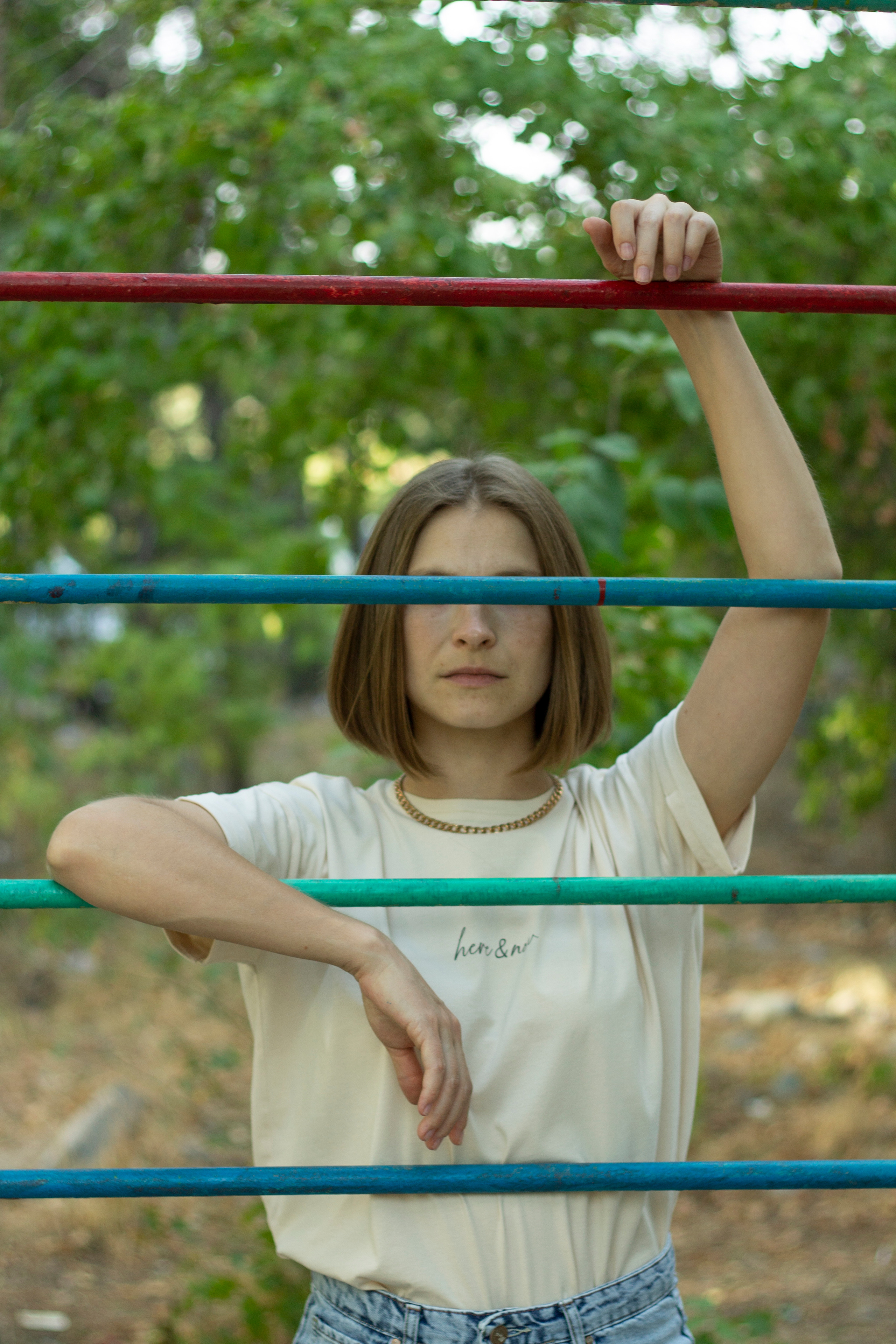 Девушка в светлой футболке стоит за турником с прикрытыми глазами