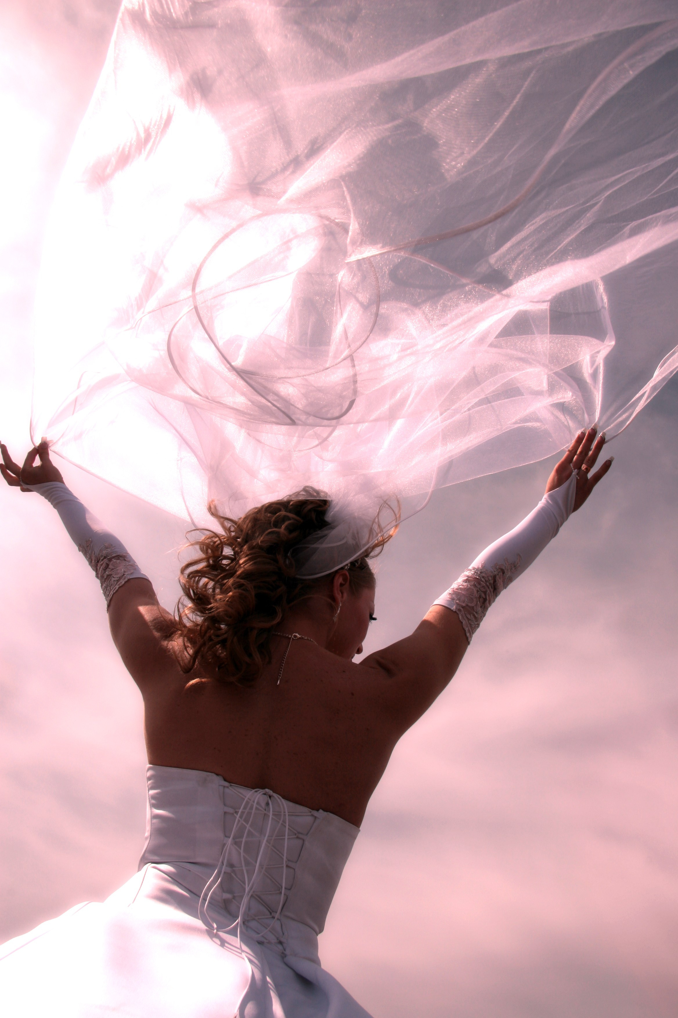 свадебная фотосессия где невеста поднимает руки вверх и держит фату взмывающую вверх